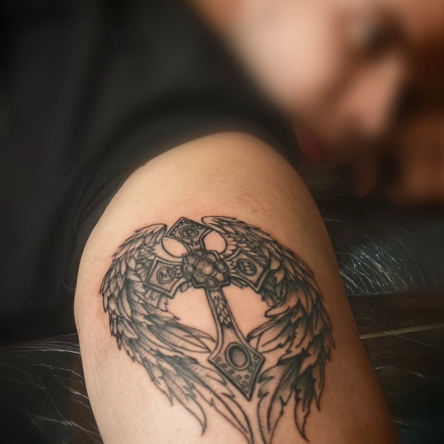 Cross with wings black and grey tattoo on the shoulder by Juanma Martin