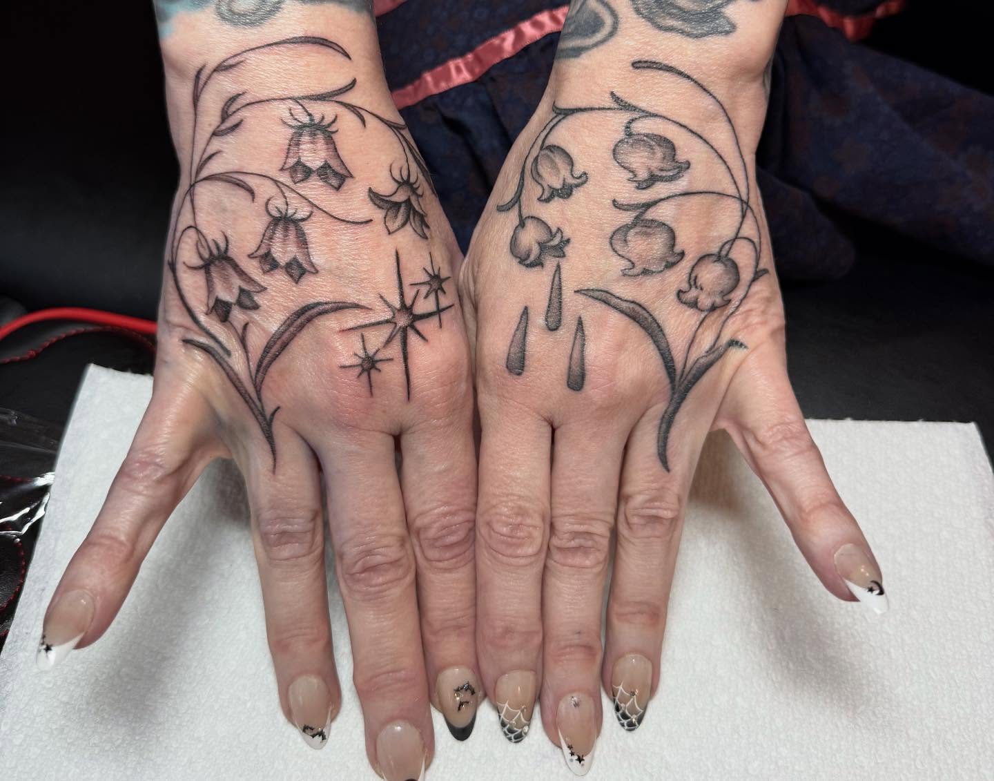 Bell flowers and starburst black and grey tattoo on the hand by Hannah Edwards, Austin, Texas