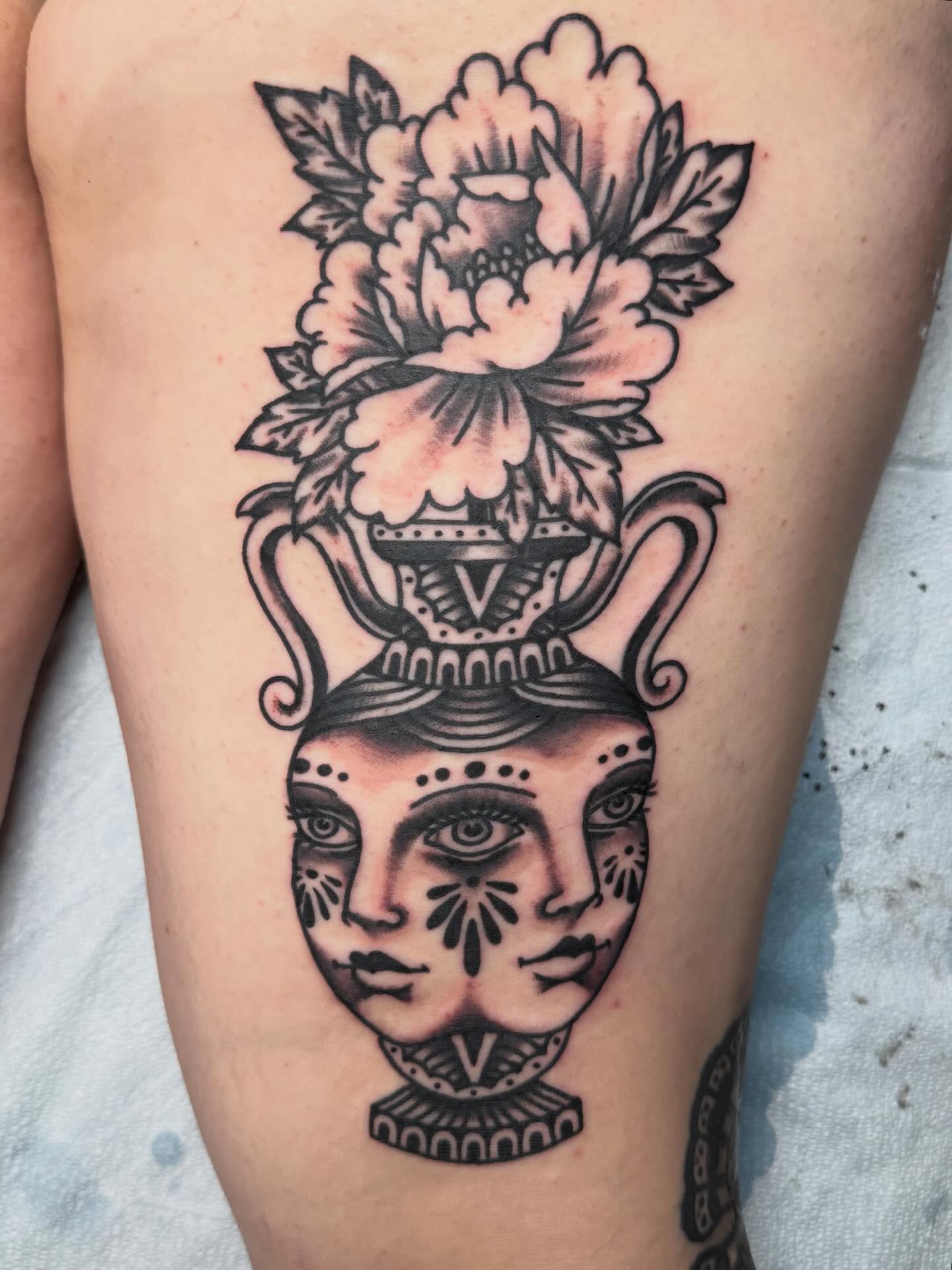 Floral vase with faces American traditional tattoo on the thigh by Bill Crawford, Plymouth, Michigan