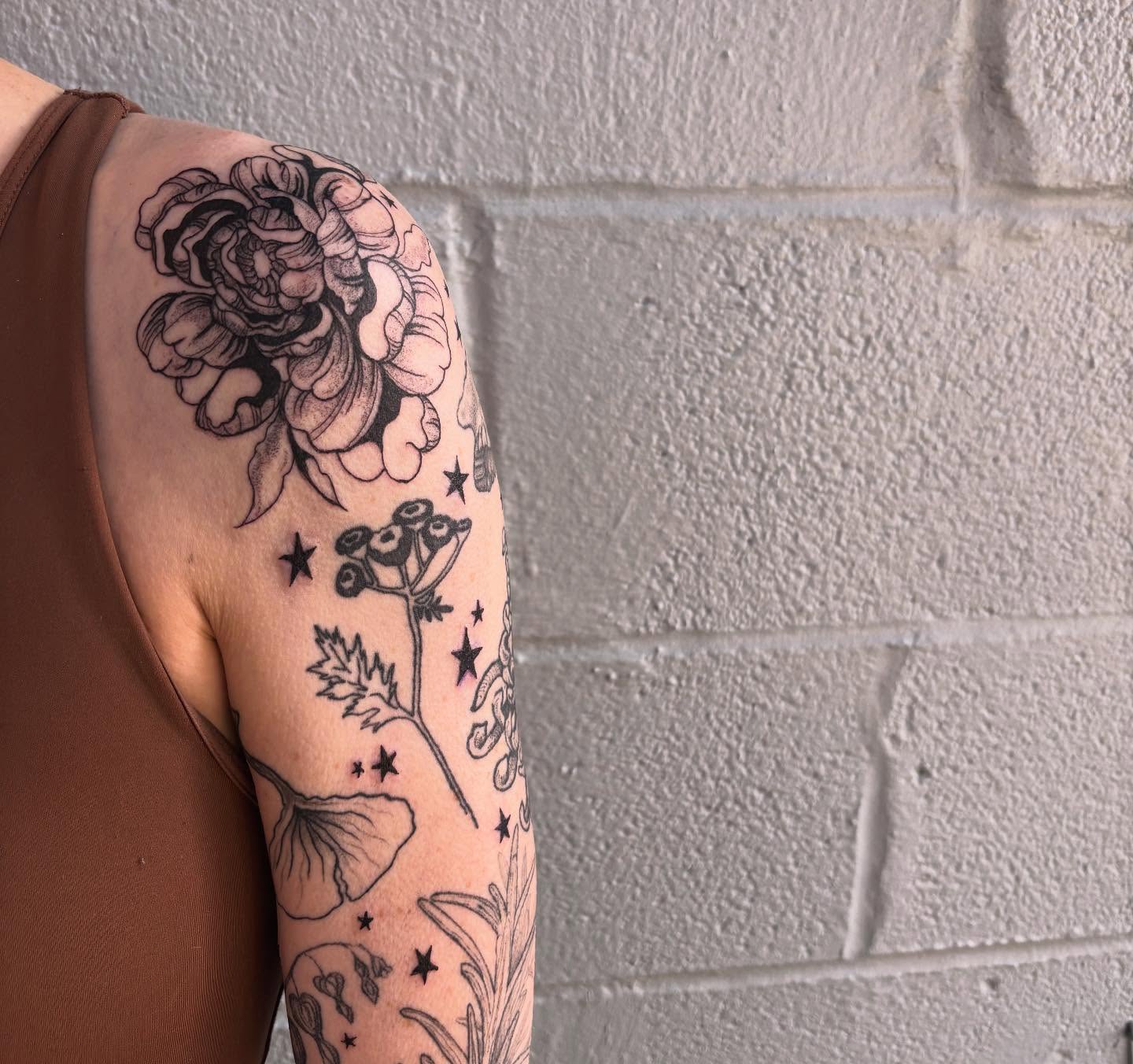 Floral bouquet black and grey tattoo on the upper arm by Ashley Ellerman