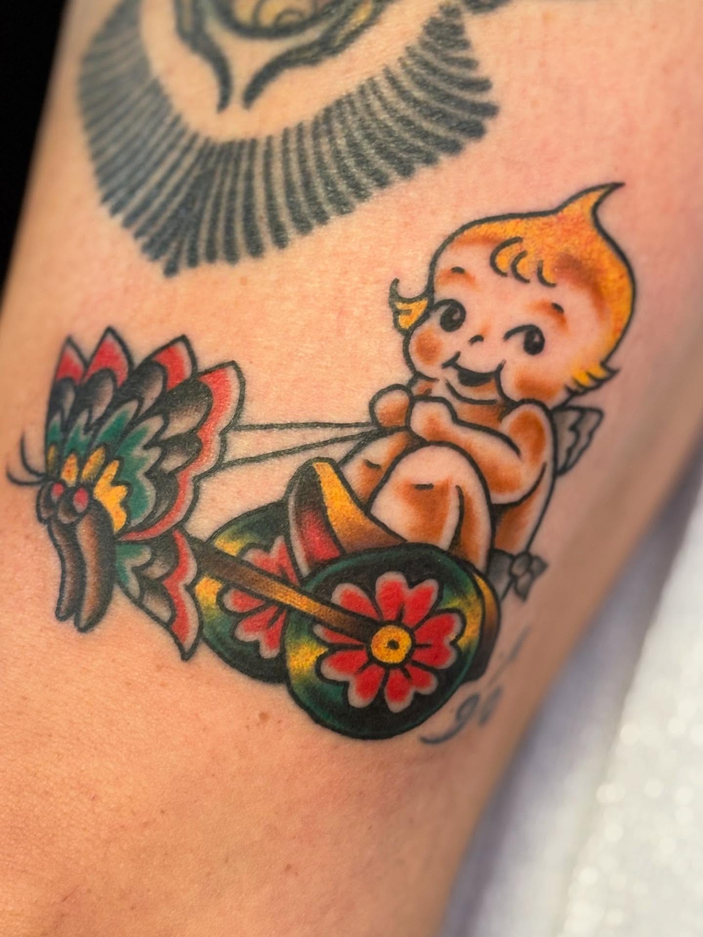 Baby on tricycle American traditional tattoo on the forearm by Angie Isbell