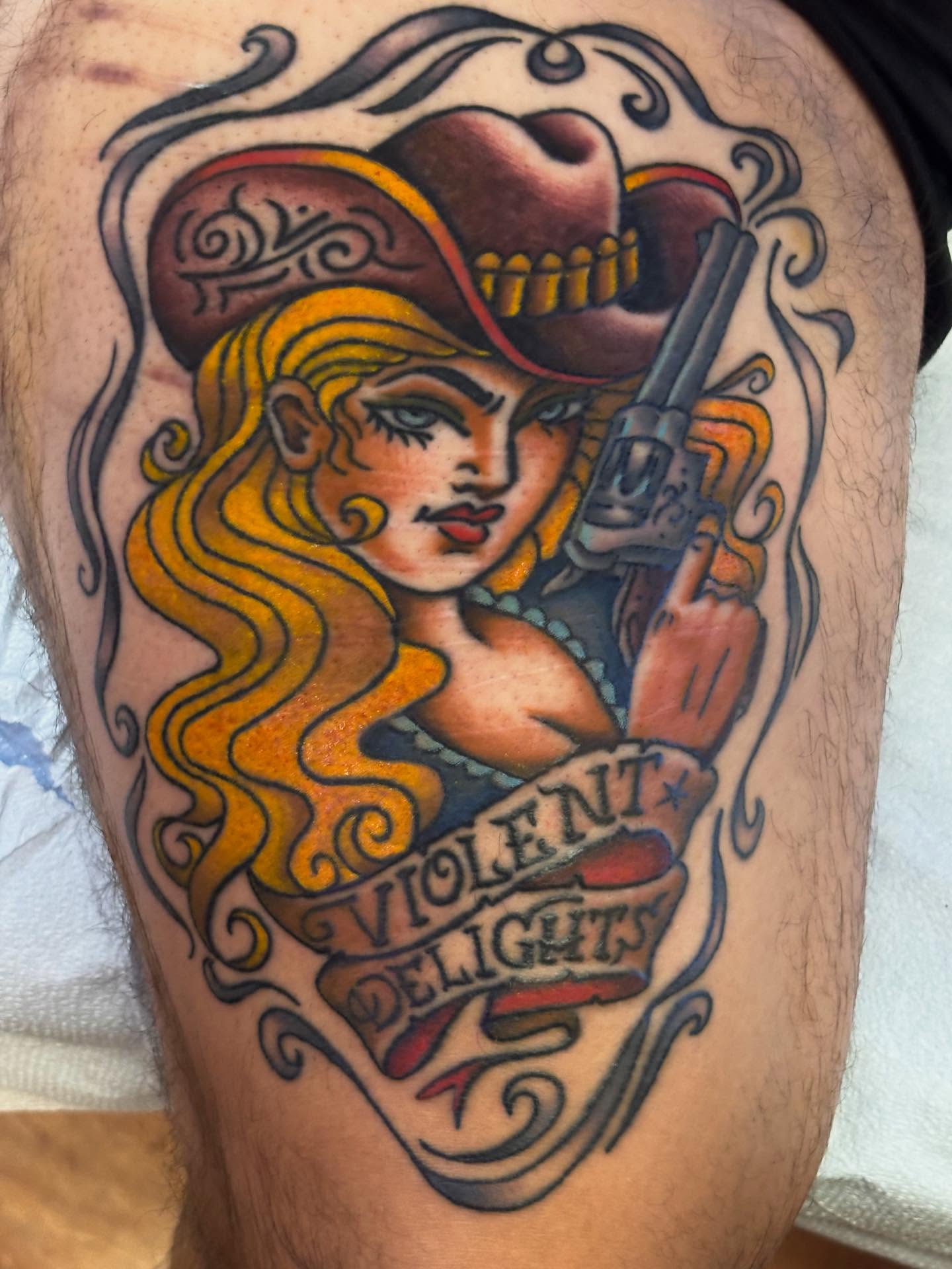 Cowgirl with revolver American traditional tattoo on the thigh by Angie Isbell