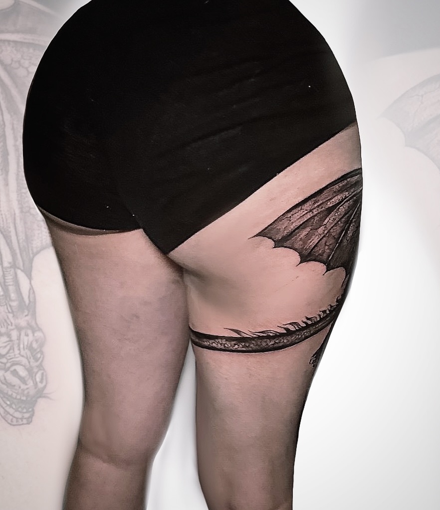 Wing black and grey tattoo on the thigh by Ken West
