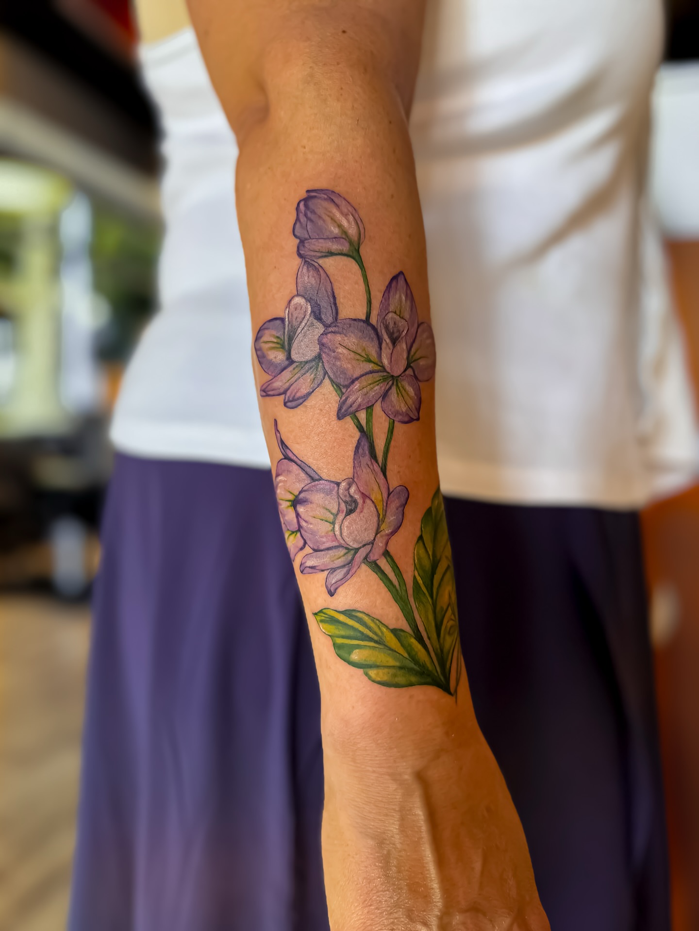 Purple flowers realism tattoo on the forearm by Amelia