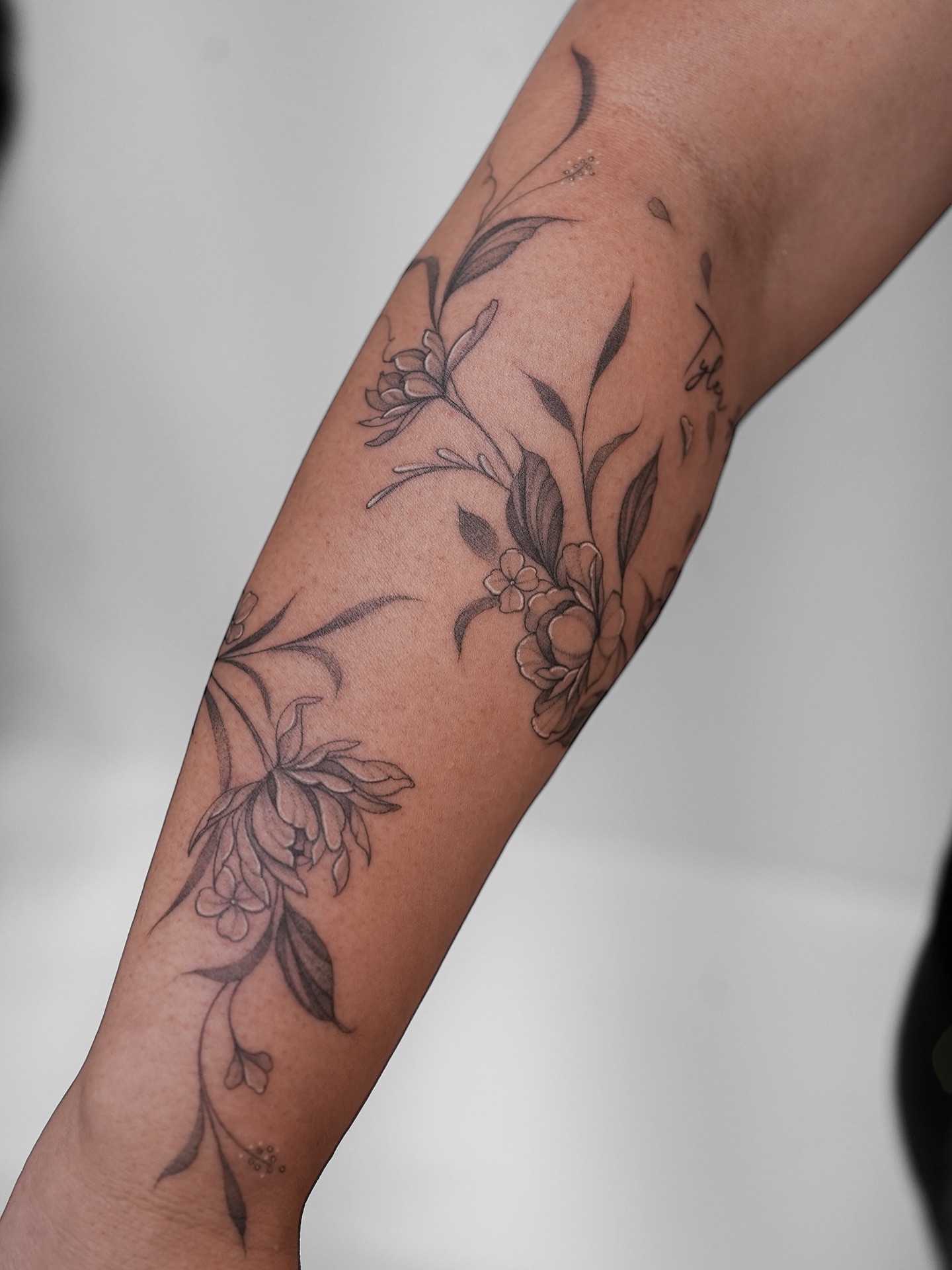 Floral arrangement black and grey tattoo on the forearm by X