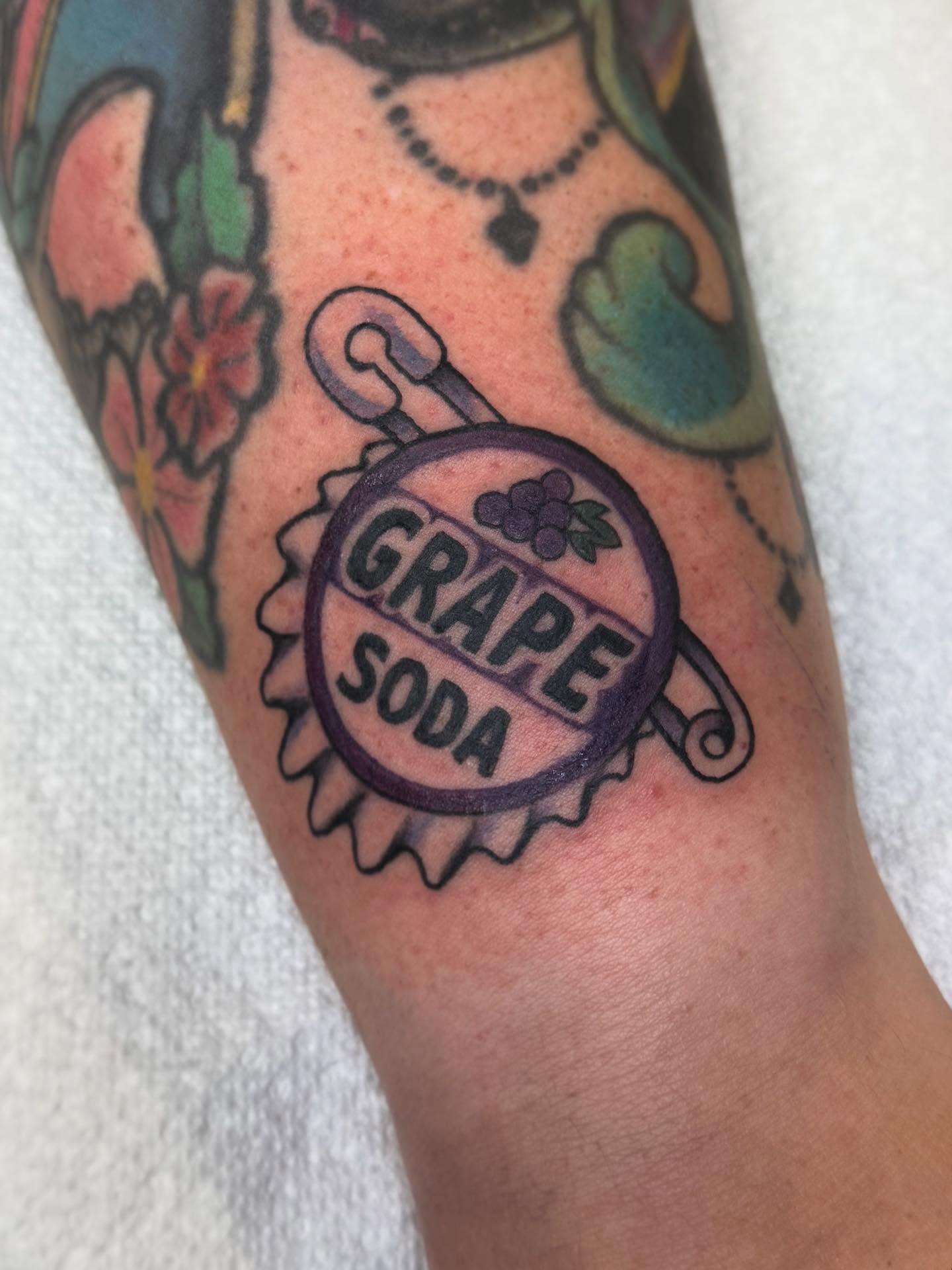 Grape soda American traditional tattoo on the forearm by Michelle