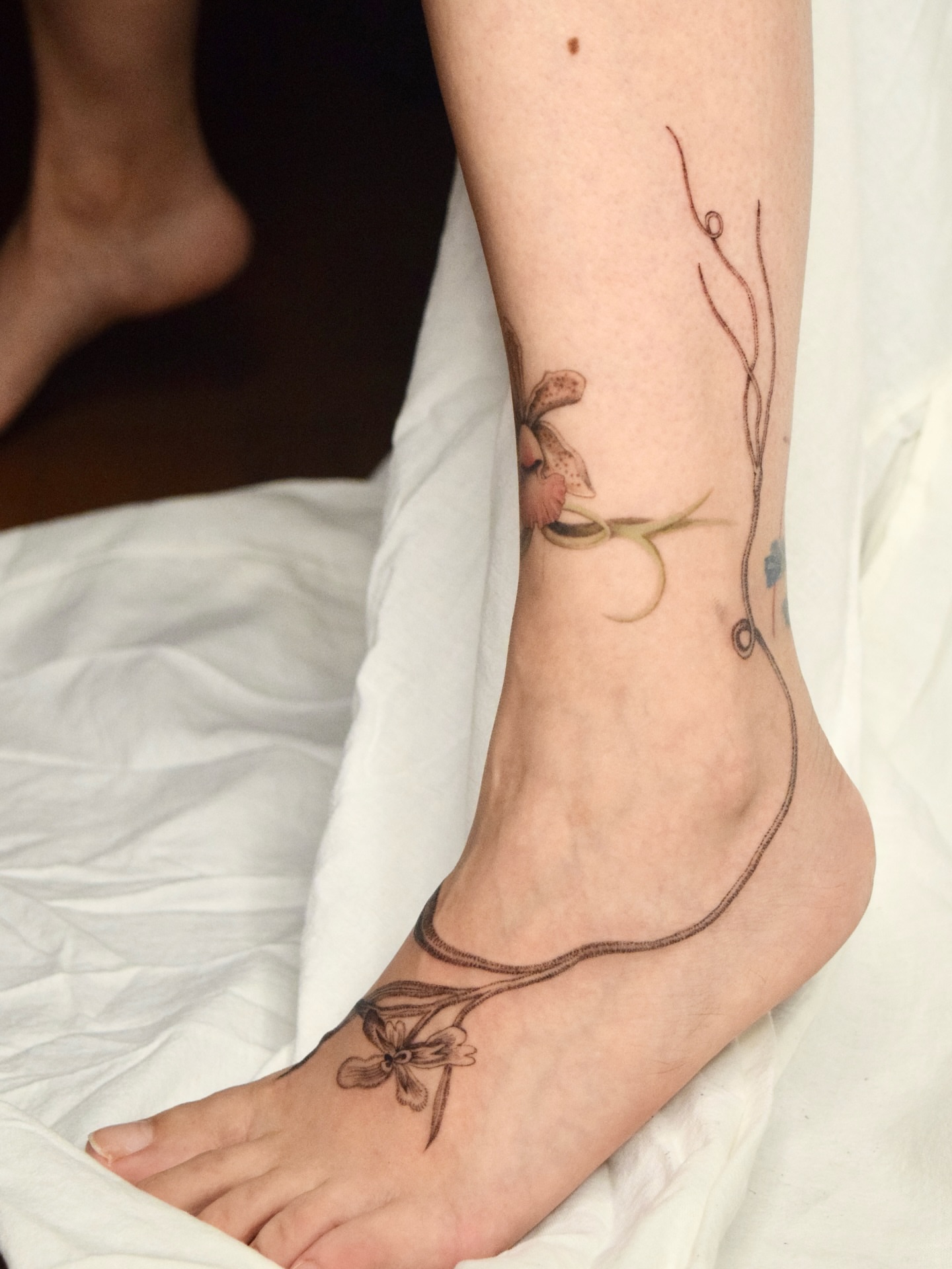 Flower and vine realism tattoo on the foot by Stella Oh