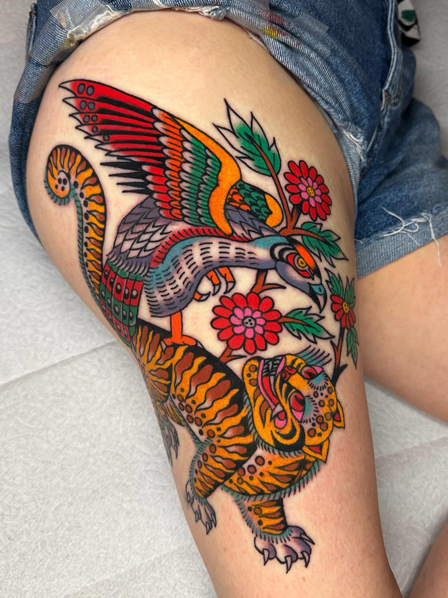 Peacock and floral American traditional tattoo on the thigh by Britt Kuechenmeister, Culver City, California