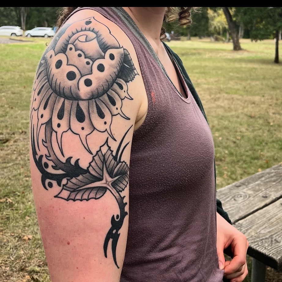 Flower black and grey tattoo on the upper arm by Ryan Willard, Denver, Colorado
