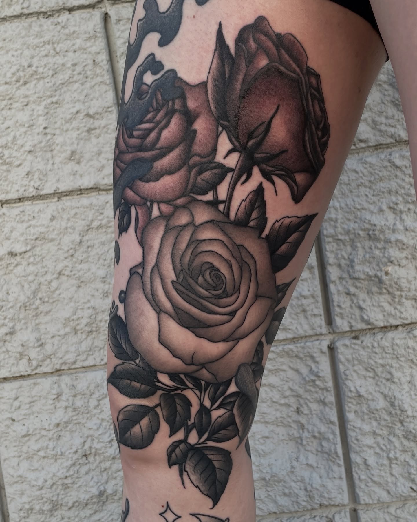 Roses black and grey tattoo on the thigh by Austin Clark