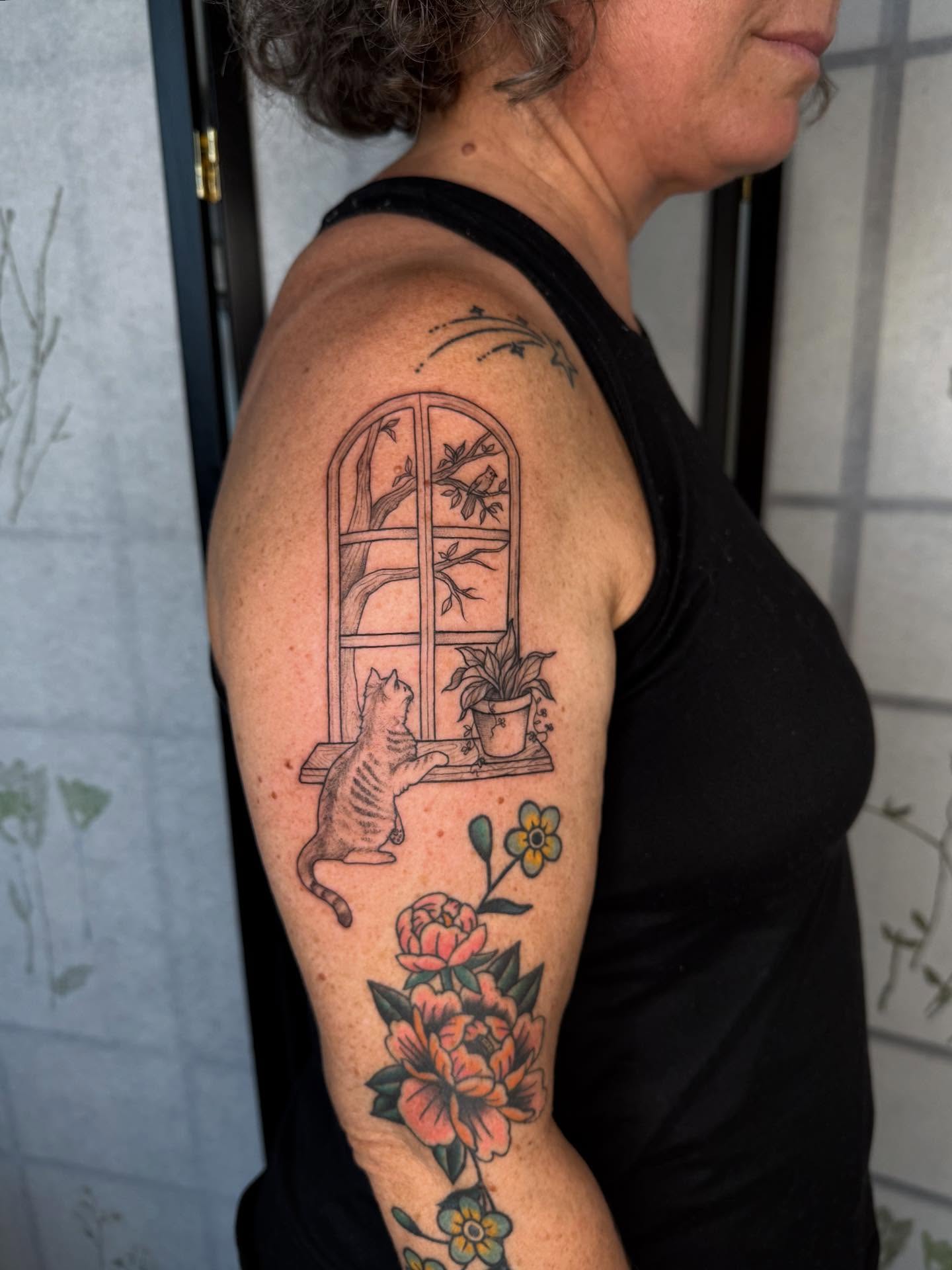 Cat and window American traditional tattoo on the upper arm by Noelle Adrienne Tattoos