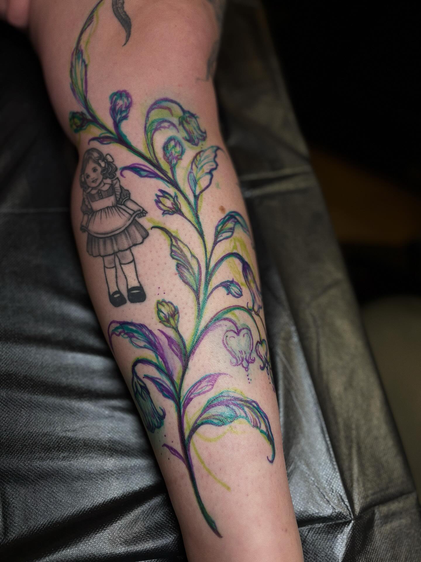 Doll and floral vine watercolor tattoo on the forearm by ๐๐ช๐ฒ๐ต๐ฎ๐ ๐๐ช๐ฎ๐ฝ๐