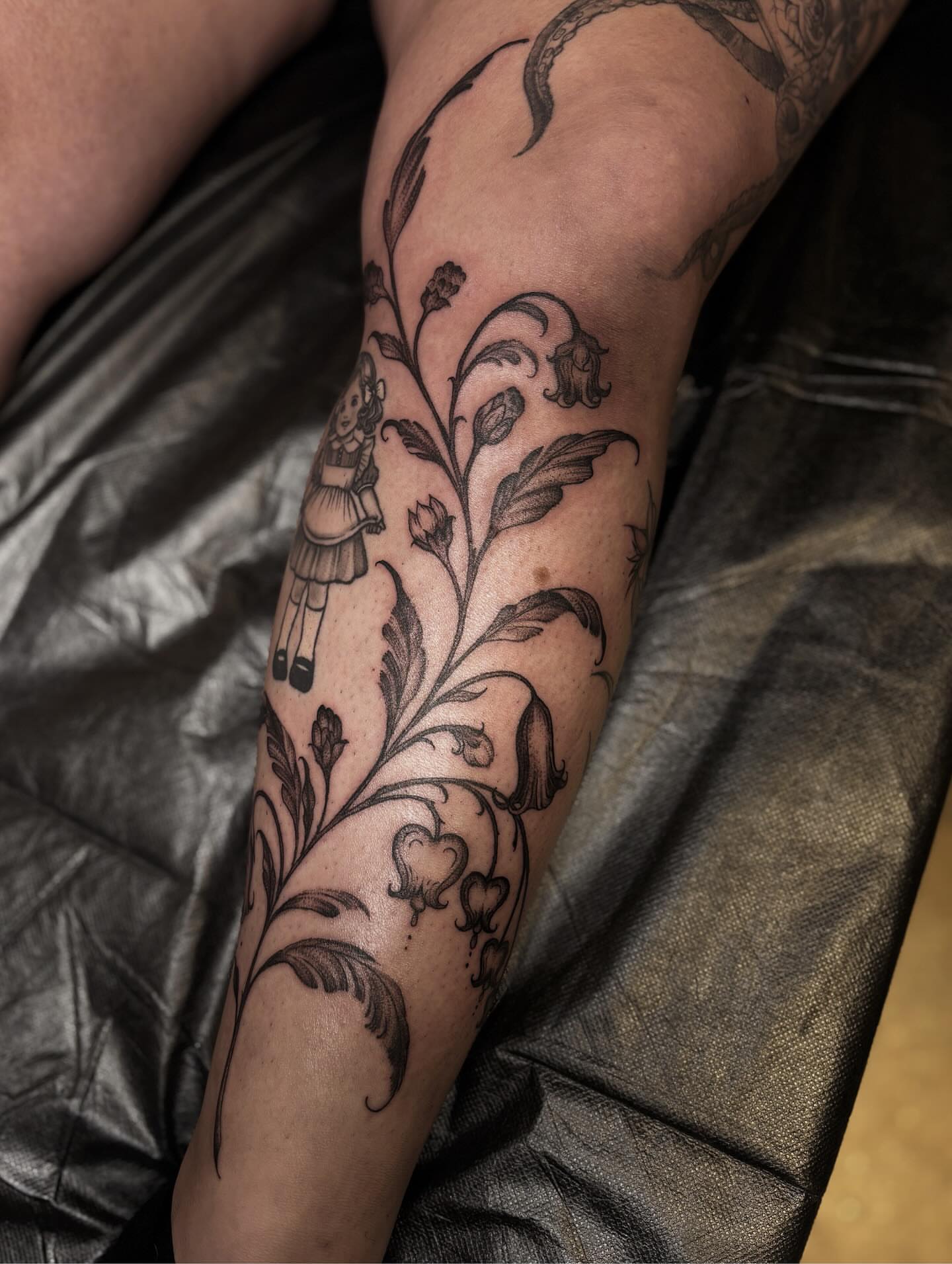 Doll and floral vine black and grey tattoo on the forearm by ๐๐ช๐ฒ๐ต๐ฎ๐ ๐๐ช๐ฎ๐ฝ๐