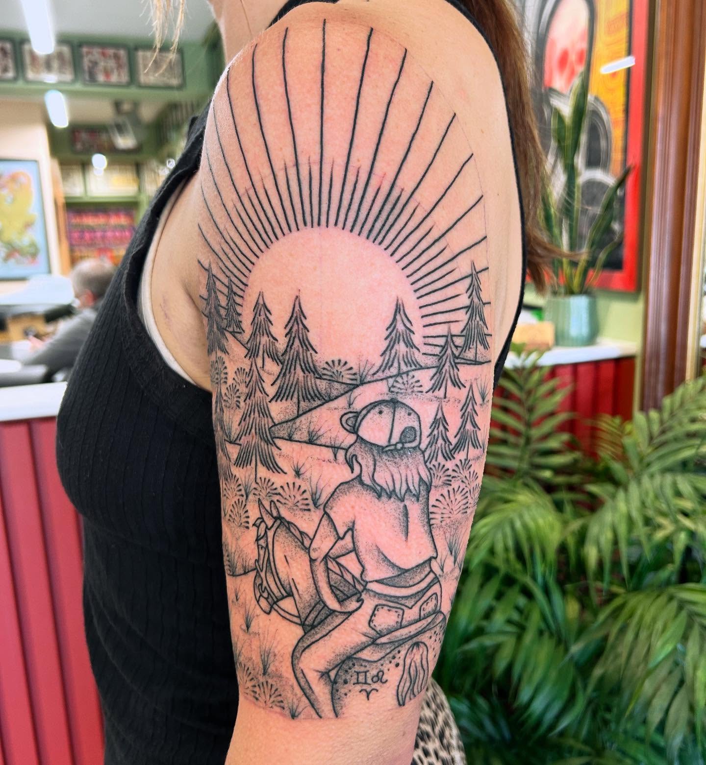 Forest scene with bear and child realism tattoo on the upper arm by Erica Finley