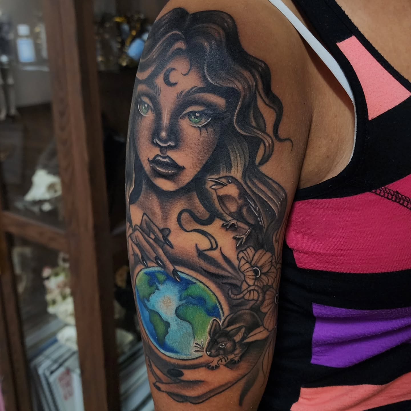 Woman with bird and globe realism tattoo on the upper arm by Shawna Goettsche