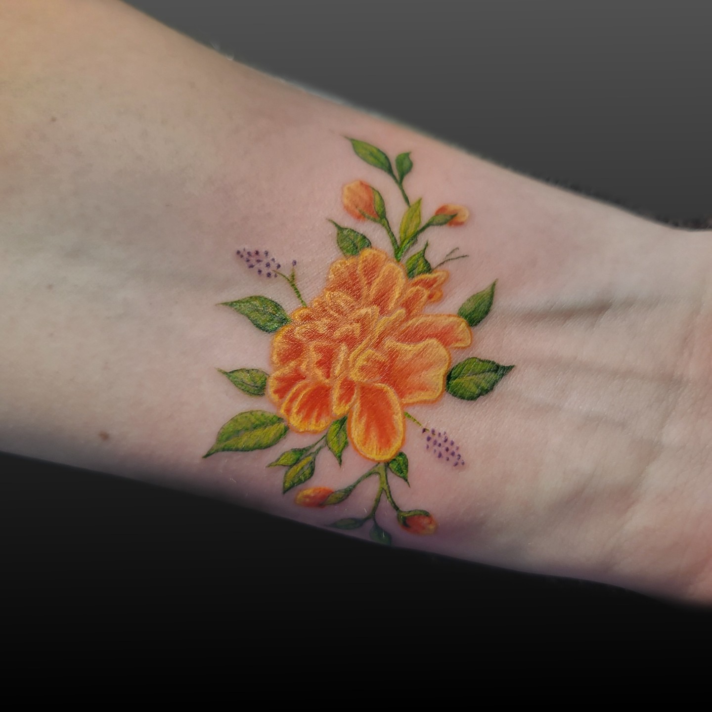 Orange flower realism tattoo on the forearm by Arick Reese