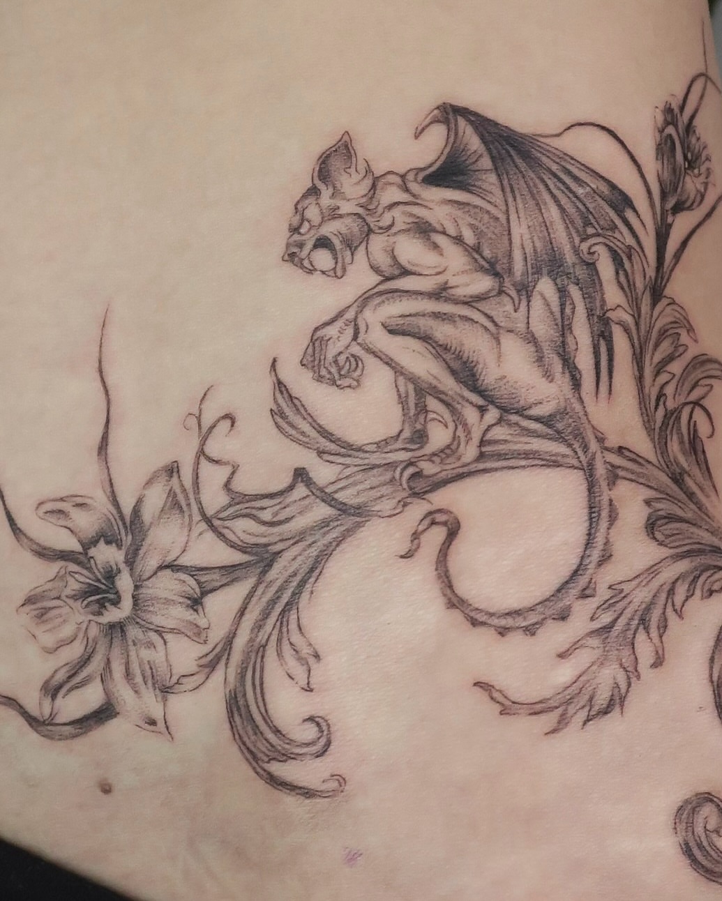 Gargoyle and flowers ornamental tattoo on the thigh by Olivia