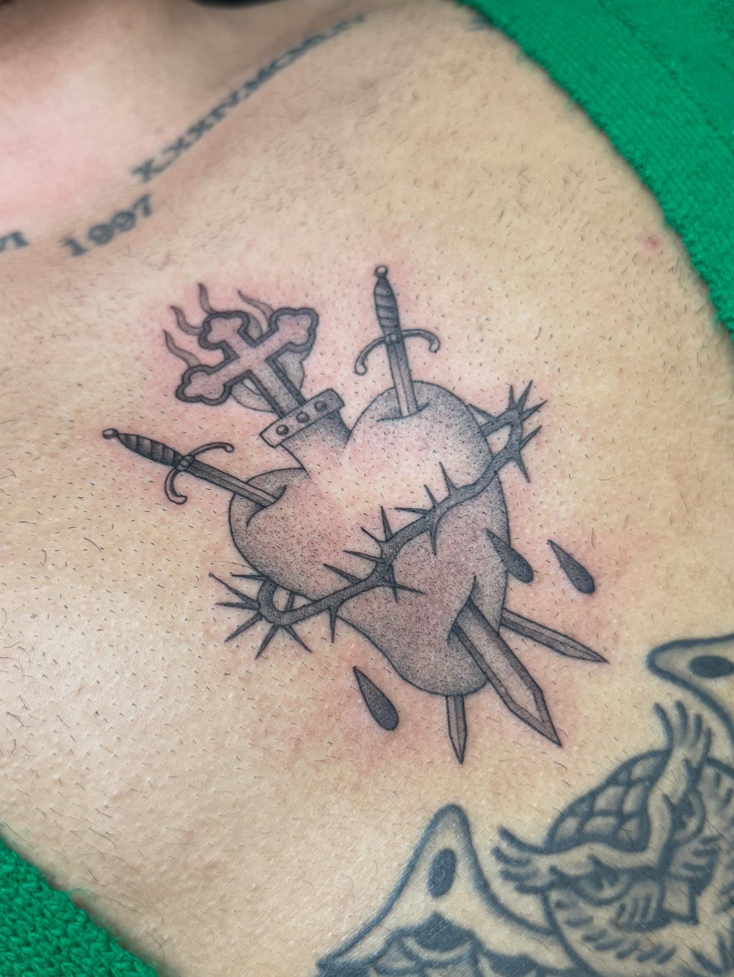 Heart with swords black and grey tattoo on the chest by Maddie Jo DeYoung