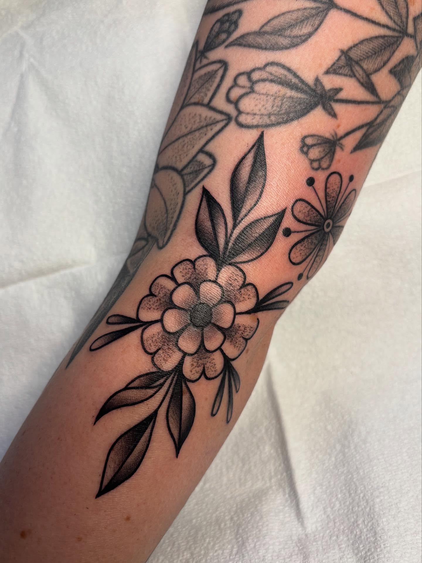 Floral arrangement black and grey tattoo on the forearm by Victoria Bacon