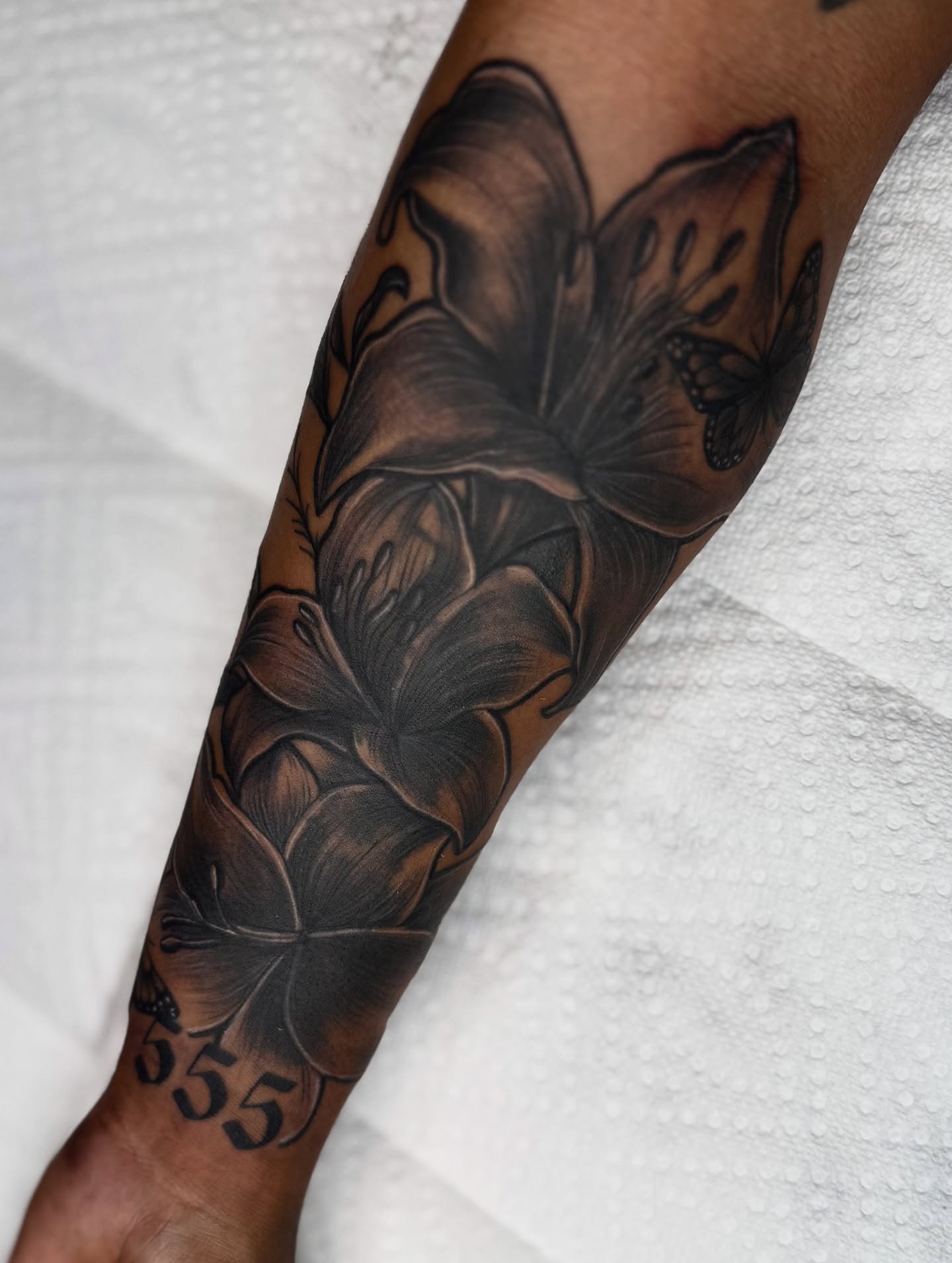 Lily flowers black and grey tattoo on the forearm by Elijah East