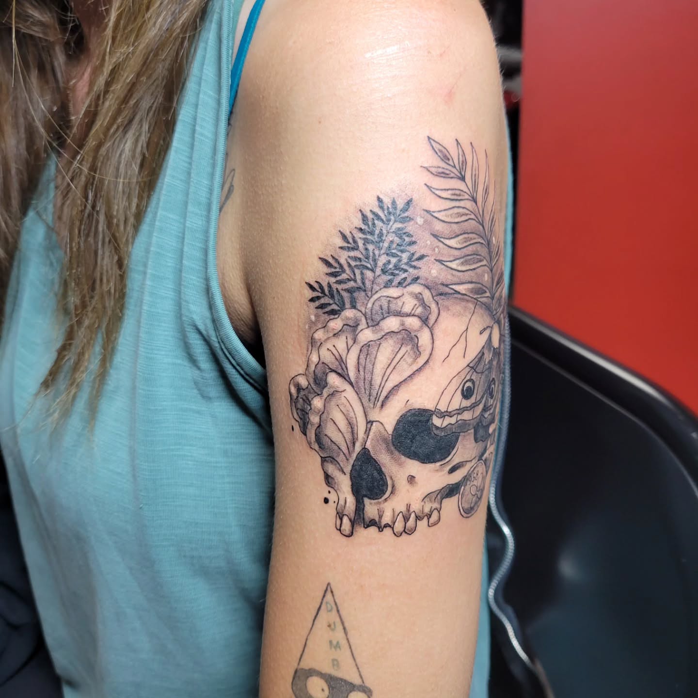 Skull with flowers realism tattoo on the forearm by Aspen C