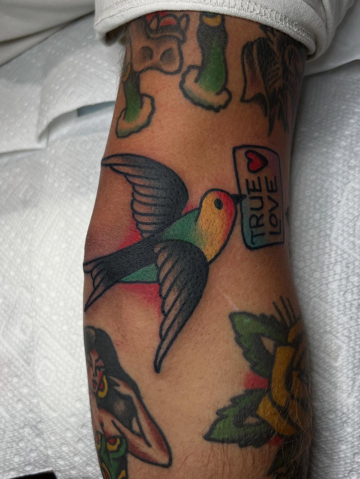 Bird and heart American traditional tattoo on the forearm by Tattoo