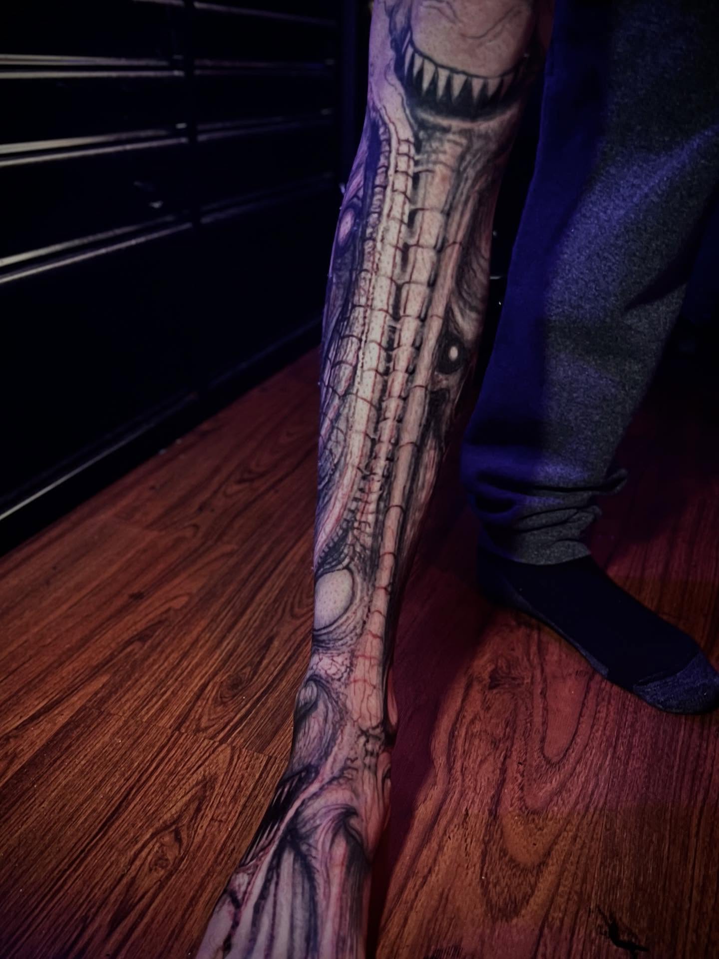 Eye and spine dark realism tattoo on the leg by Paul Booth