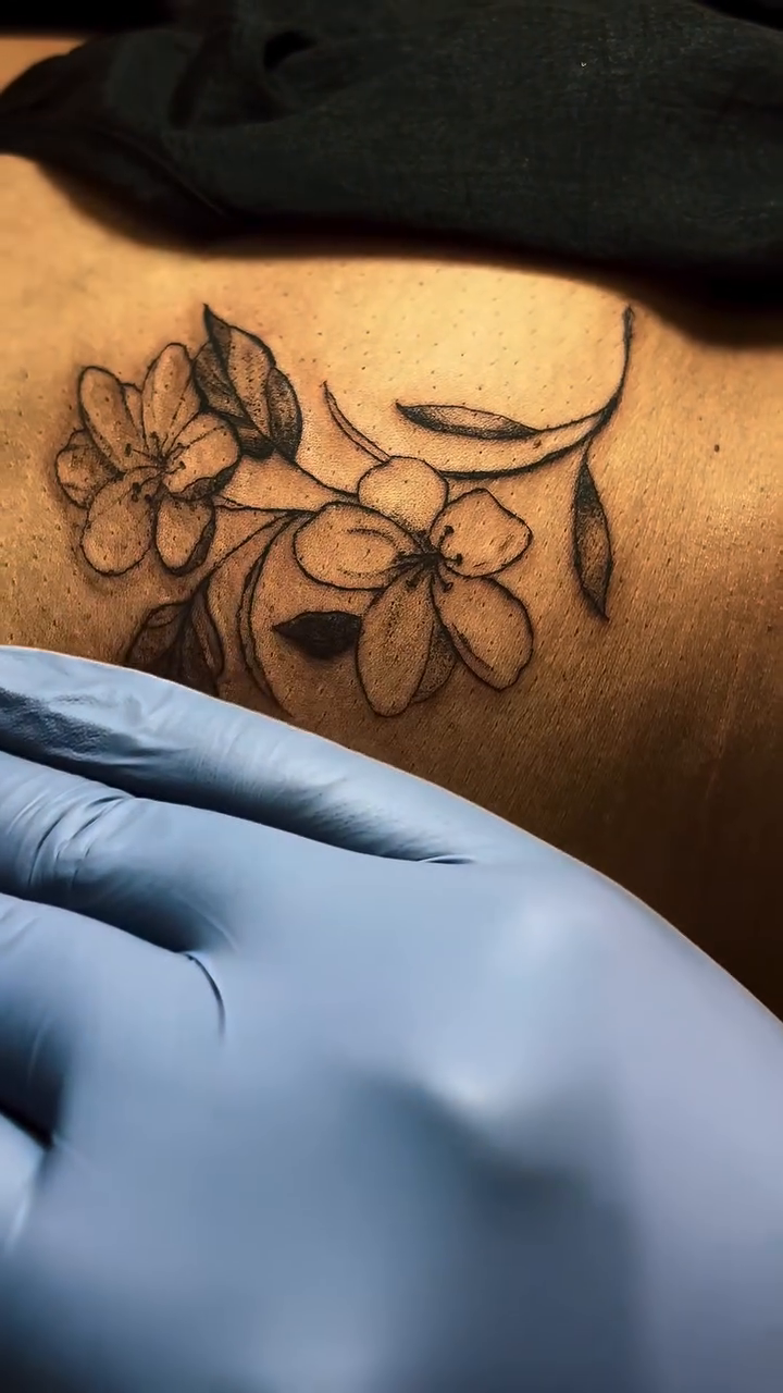 Floral branch fine line tattoo on the upper arm by Lopez Dautruche