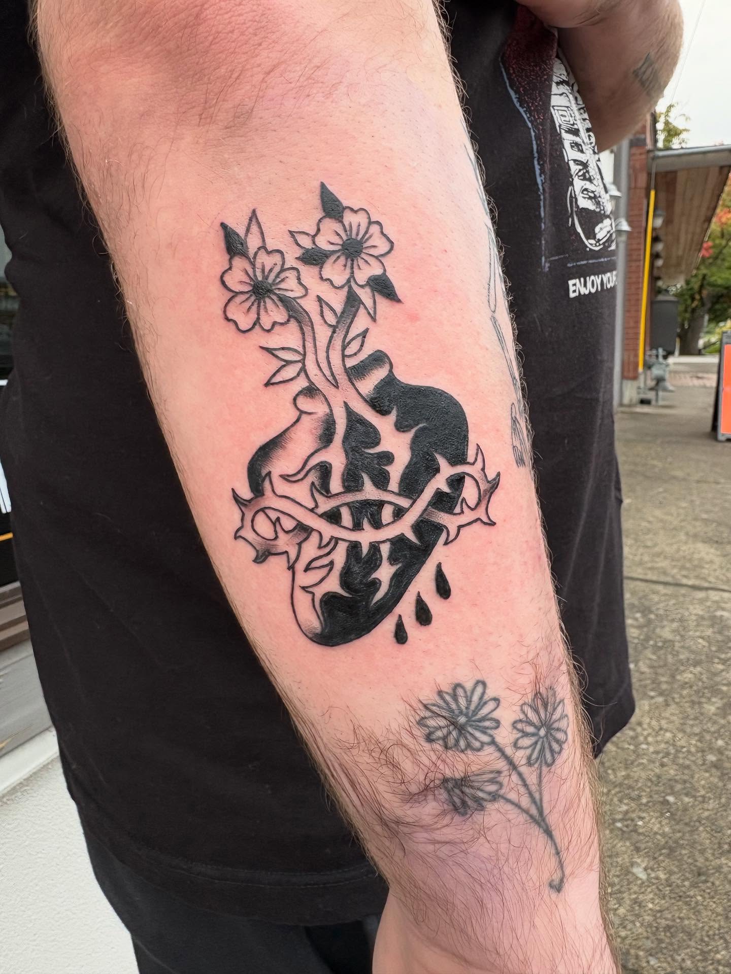 Heart with thorns and flowers neo-traditional tattoo on the forearm by ellie