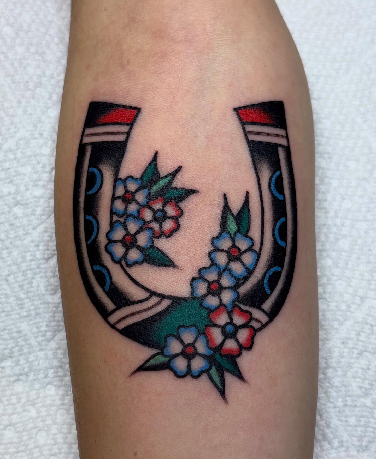 Horseshoe with flowers American traditional tattoo on the forearm by Izzy