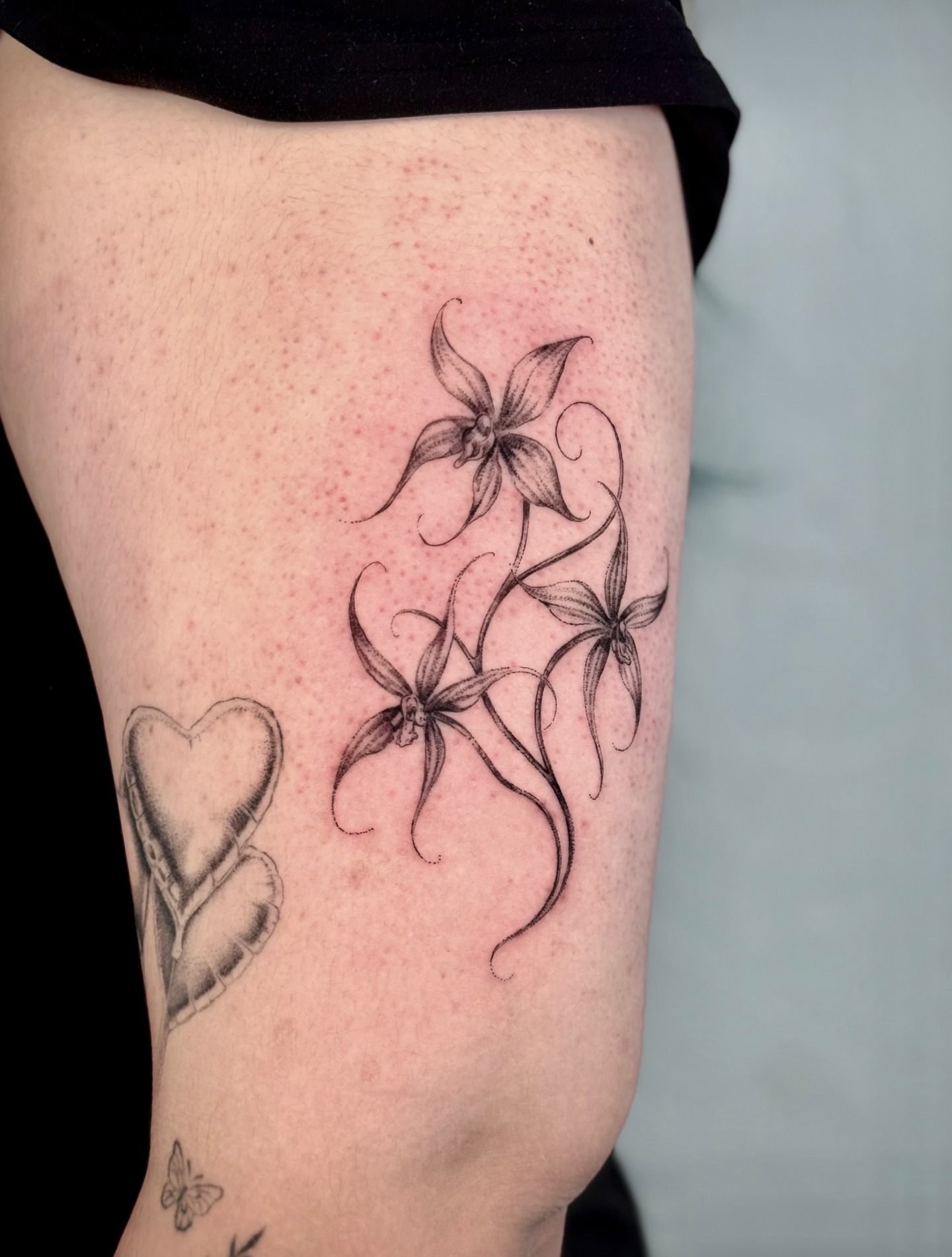Flowers and heart black and grey tattoo on the thigh by Mariana; Fine Line Tattoo Artist