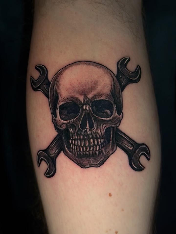 Skull and wrenches black and grey tattoo on the forearm by Therapy ink