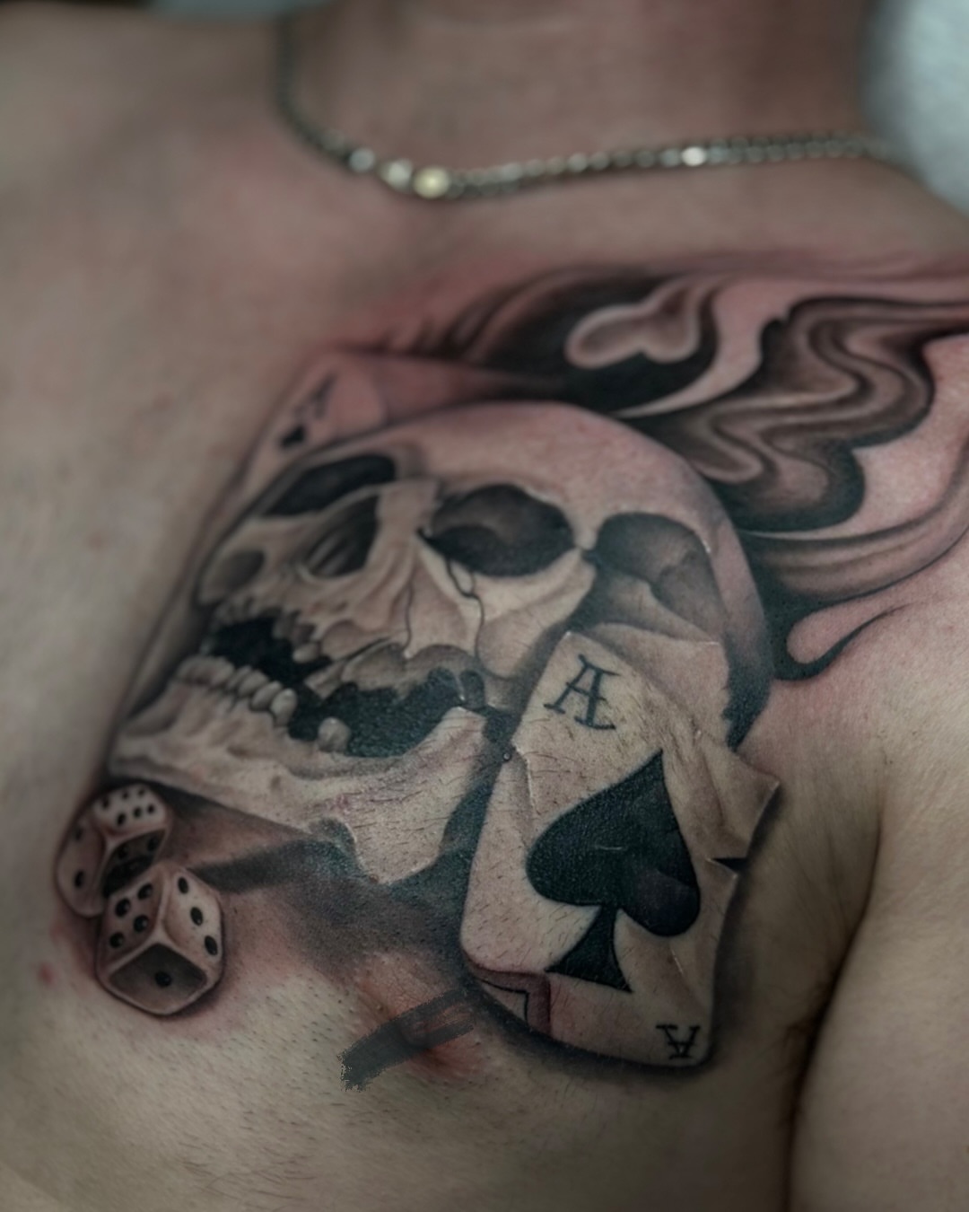 Skull and playing card American traditional tattoo on the chest by Iryna Polyakhova
