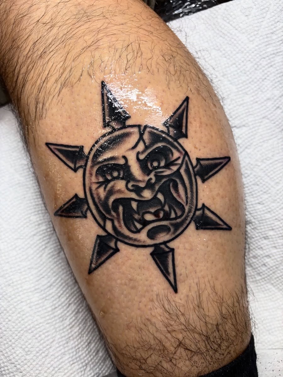 Sun with face black and grey tattoo on the forearm by Nick