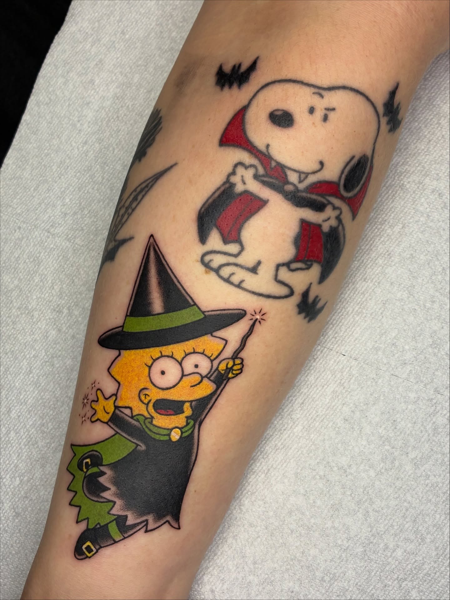 Halloween-themed Snoopy and Lisa Simpson American traditional tattoo on the forearm by Lance 🦈