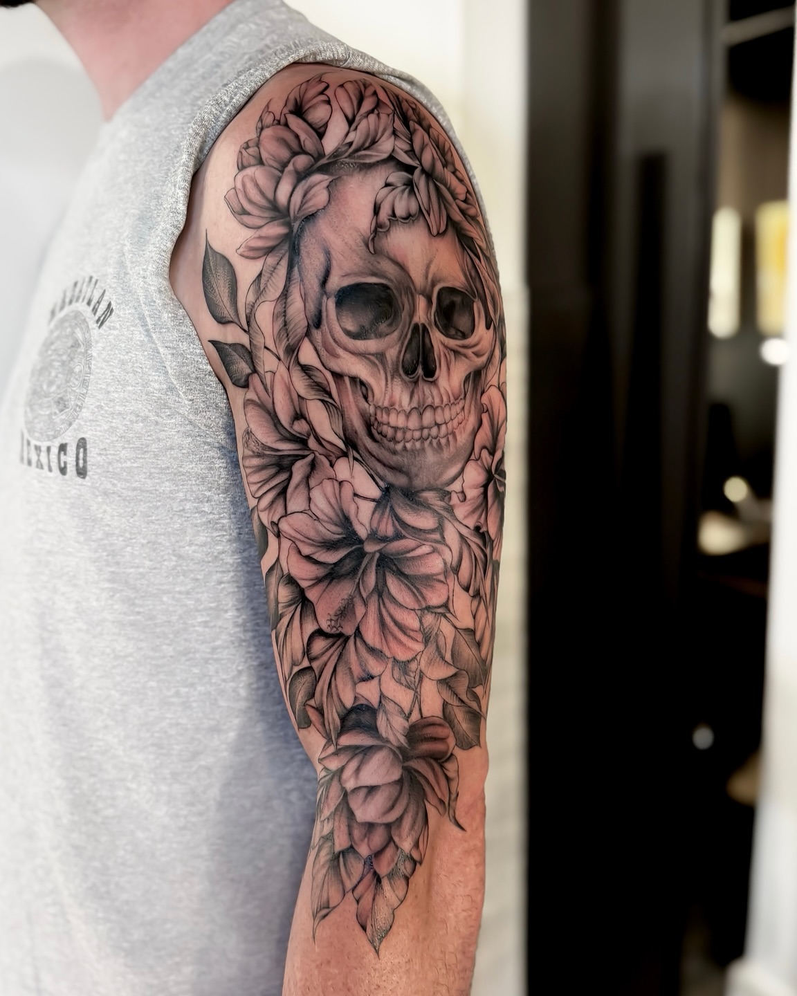 Skull and flowers realism tattoo on the forearm by Amelia