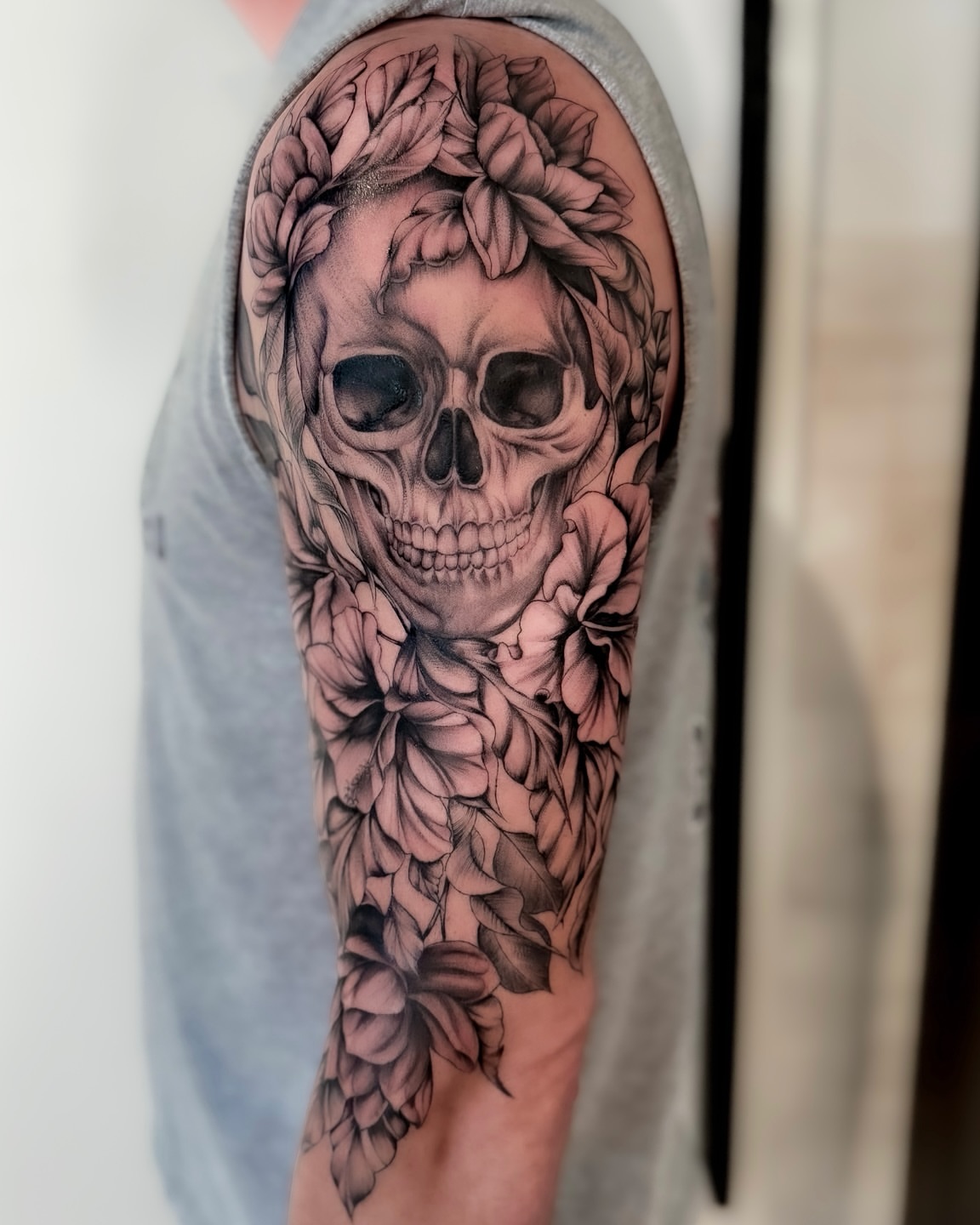 Skull with floral wreath realism tattoo on the forearm by Amelia