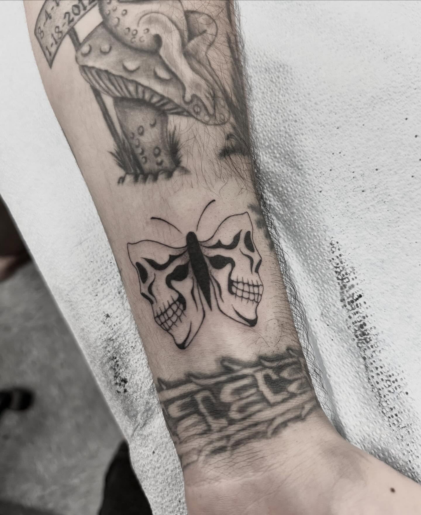 Skull and butterfly black and grey tattoo on the forearm by ππππππ