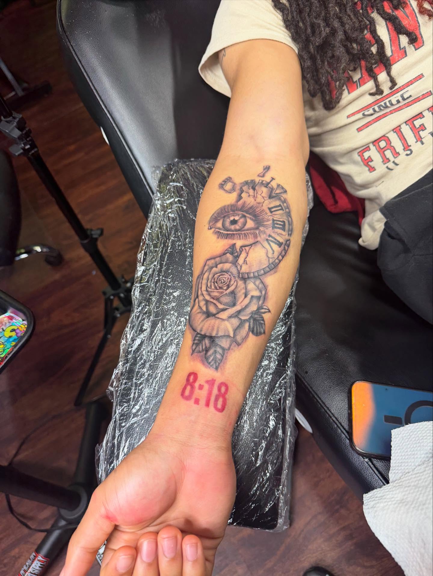 Eye and clock with rose black and grey tattoo on the forearm by Glass Inkk