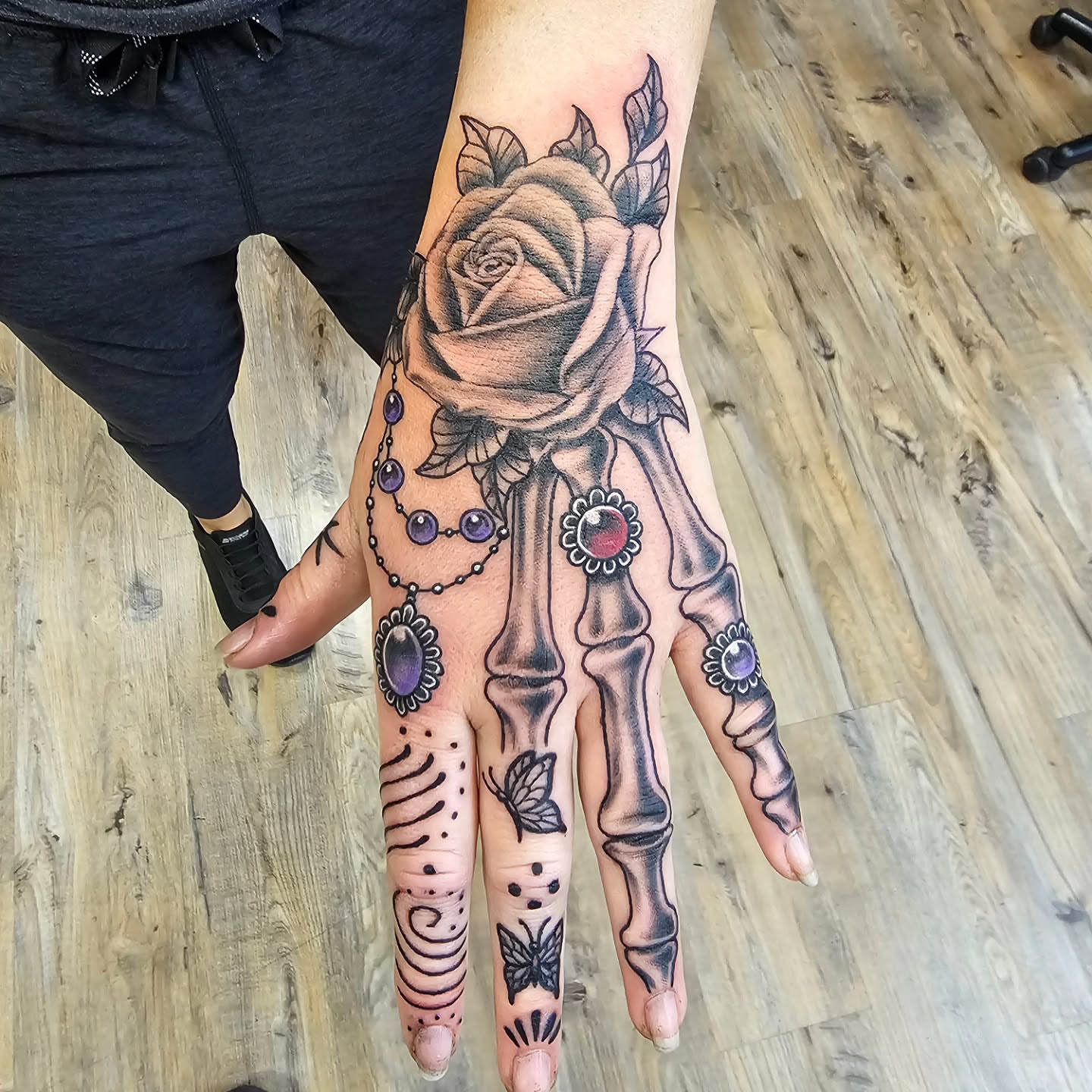 Skeleton hand with rose realism tattoo on the hand by Derek Davis