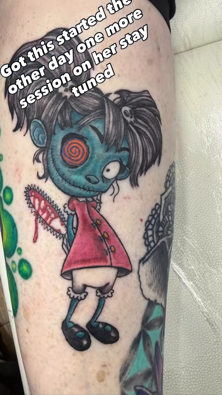 Zombie doll with chainsaw neo-traditional tattoo on the upper arm by Jason Topliss