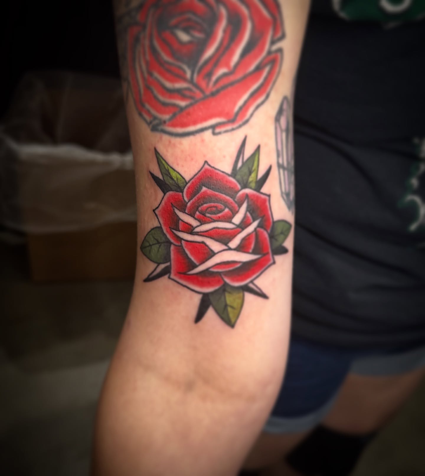 Red roses American traditional tattoo on the forearm by Elizabeth’s Eclectic Tattoos