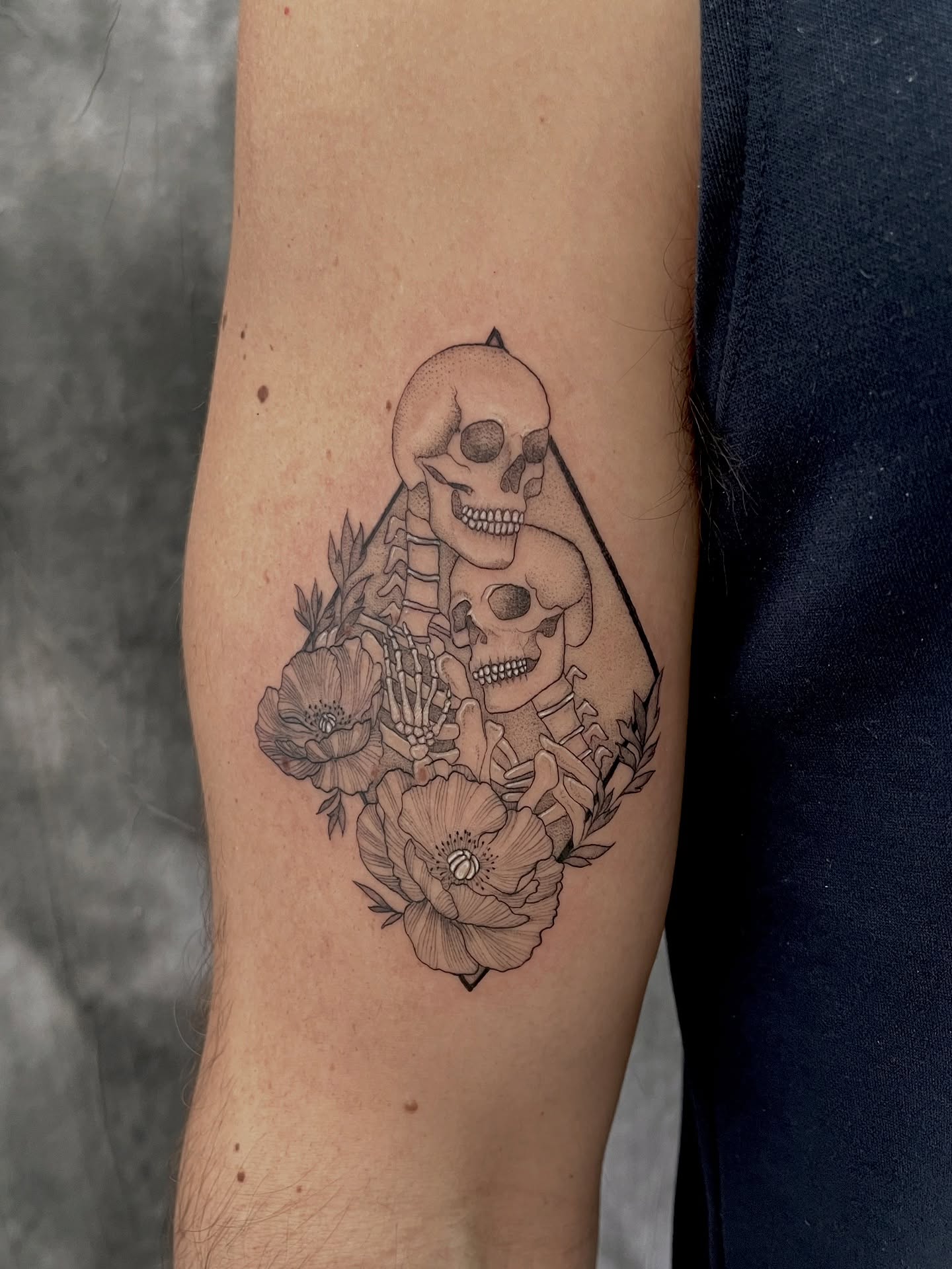 Skulls and flowers geometric tattoo on the forearm by Lo Gwynn