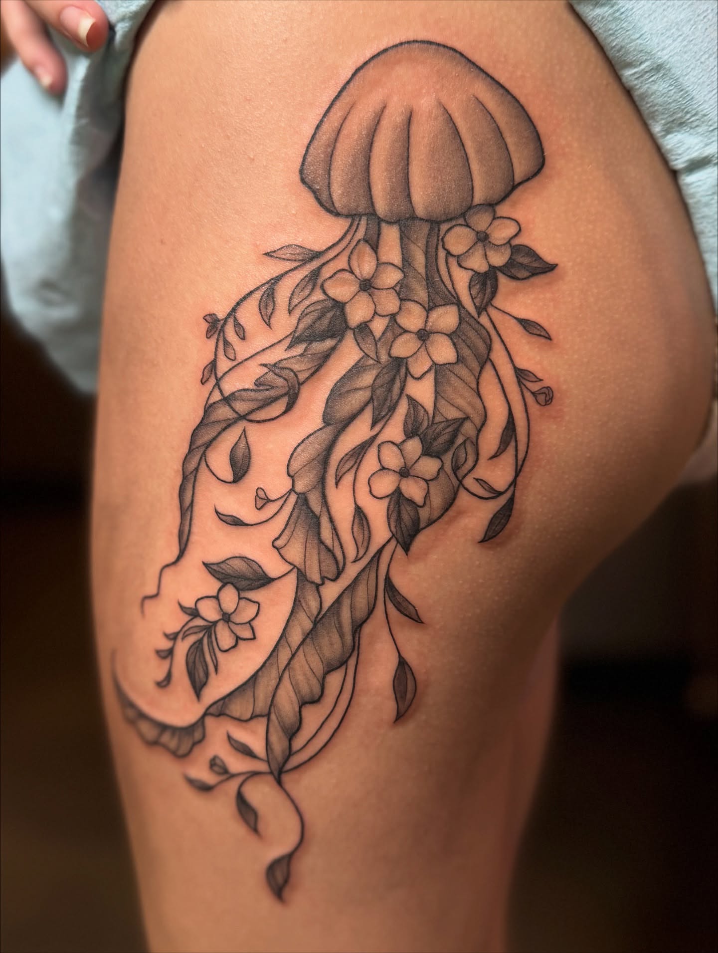 Jellyfish with flowers black and grey tattoo on the thigh by Lily Bejarno