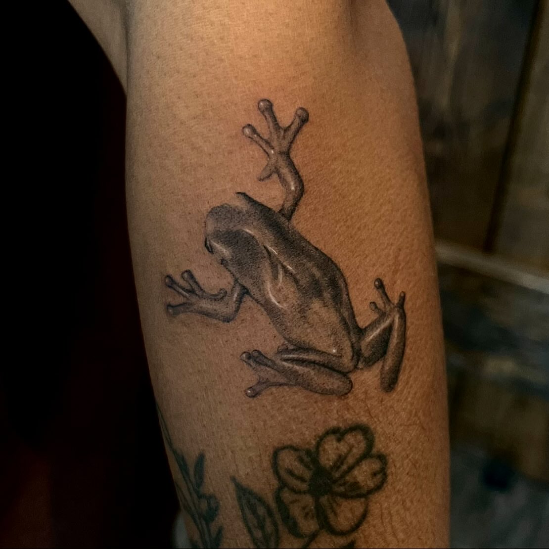Frog black and grey tattoo on the forearm by Lee Ranco