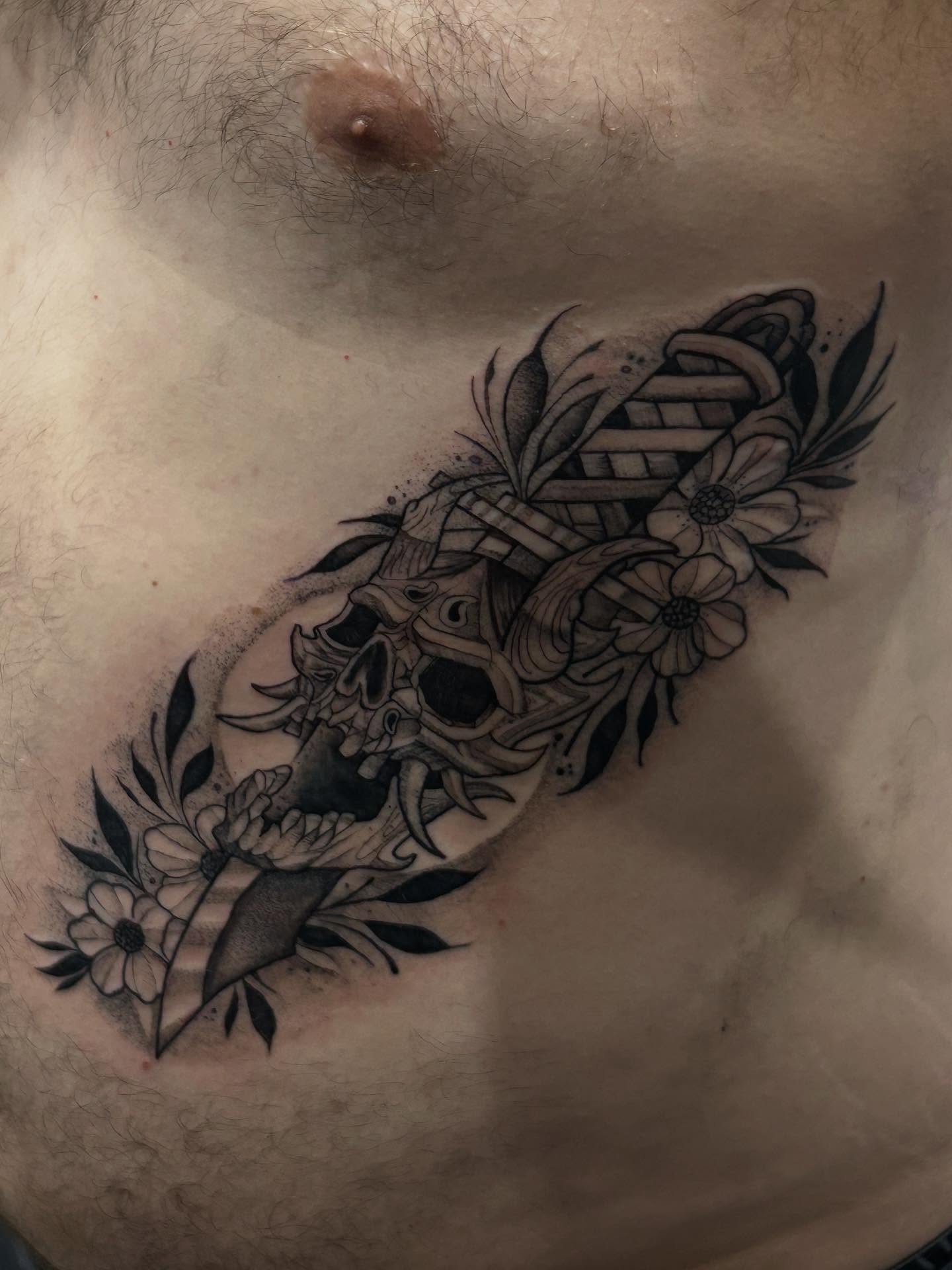 Skull and flowers black and grey tattoo on the chest by Cyko Hernandez