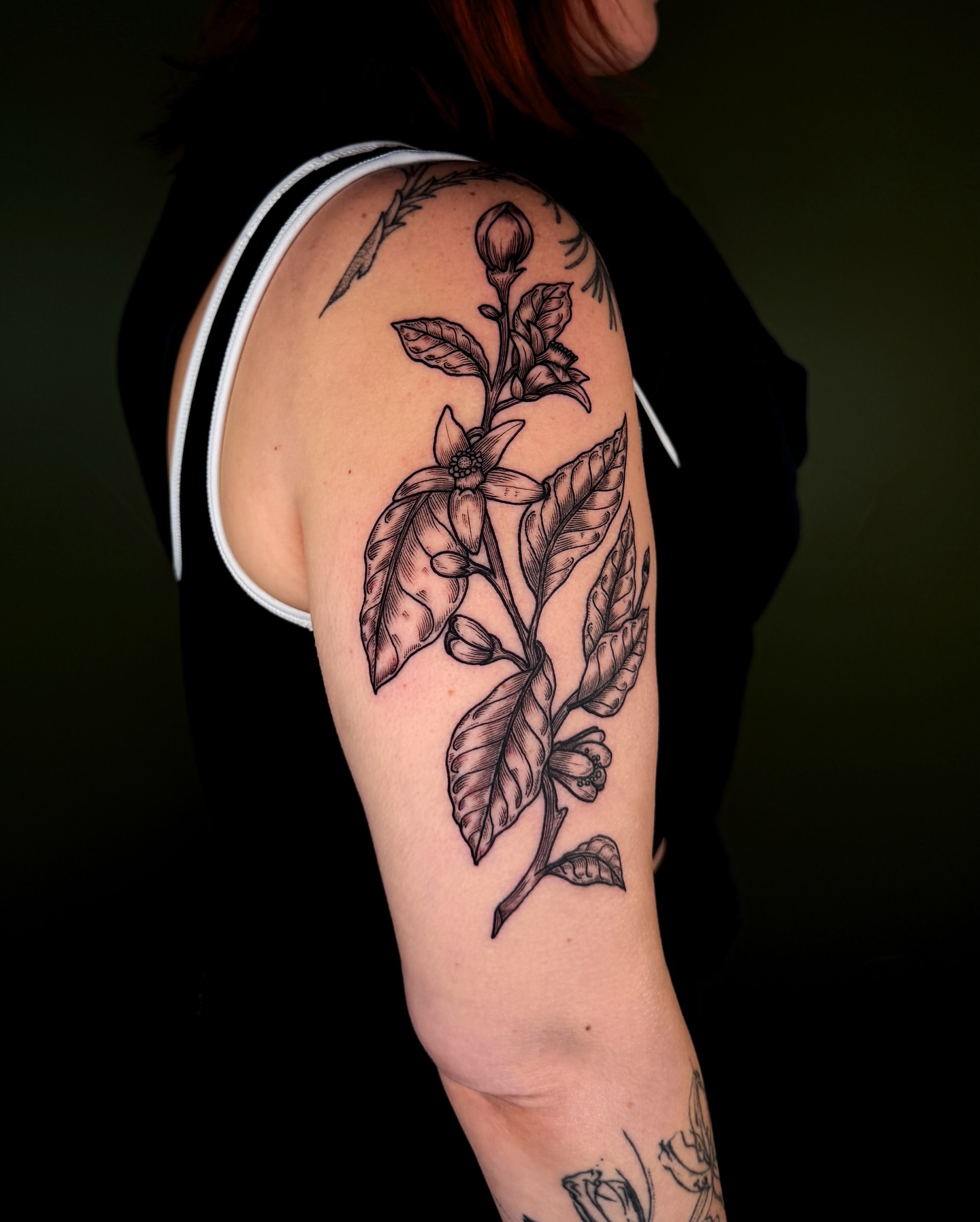Flower and leaves black and grey tattoo on the upper arm by Zella Mäkelä