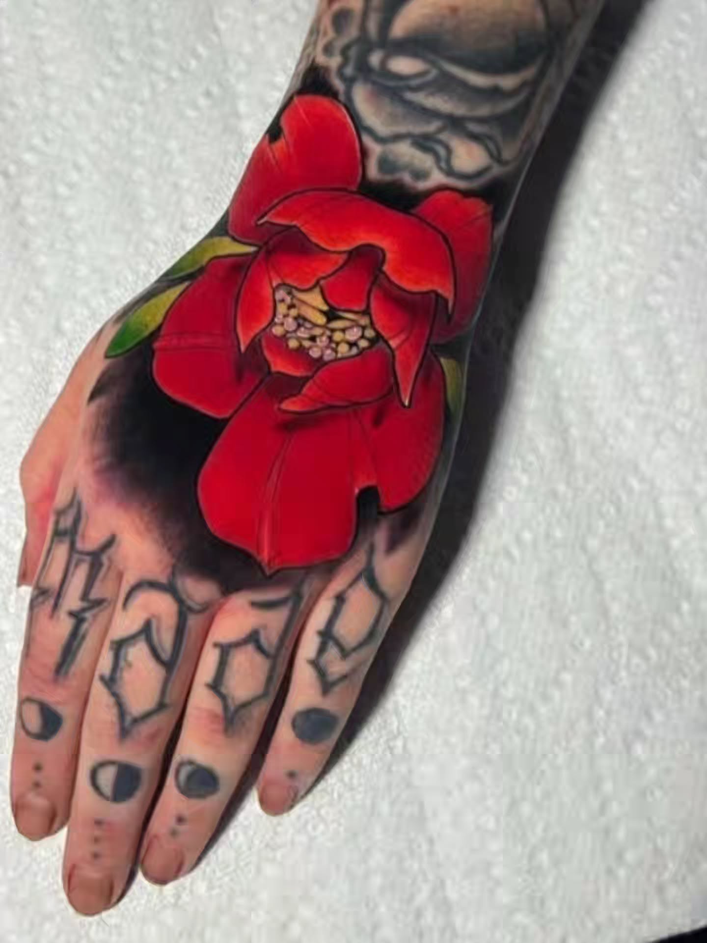 Red flower realism tattoo on the hand by SJ Horvath