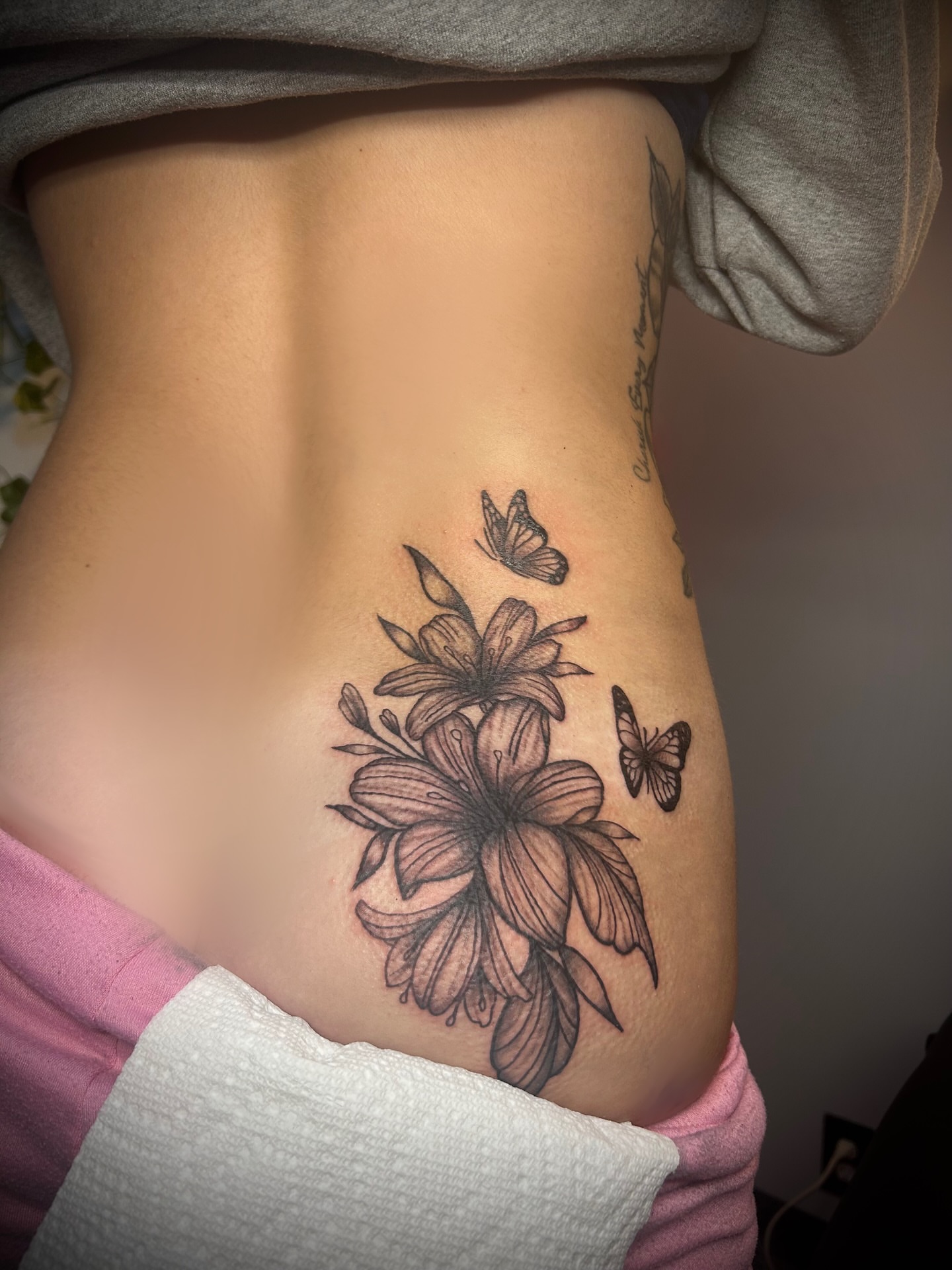 Flowers and butterflies black and grey tattoo on the ribs by Kiersten Tickle