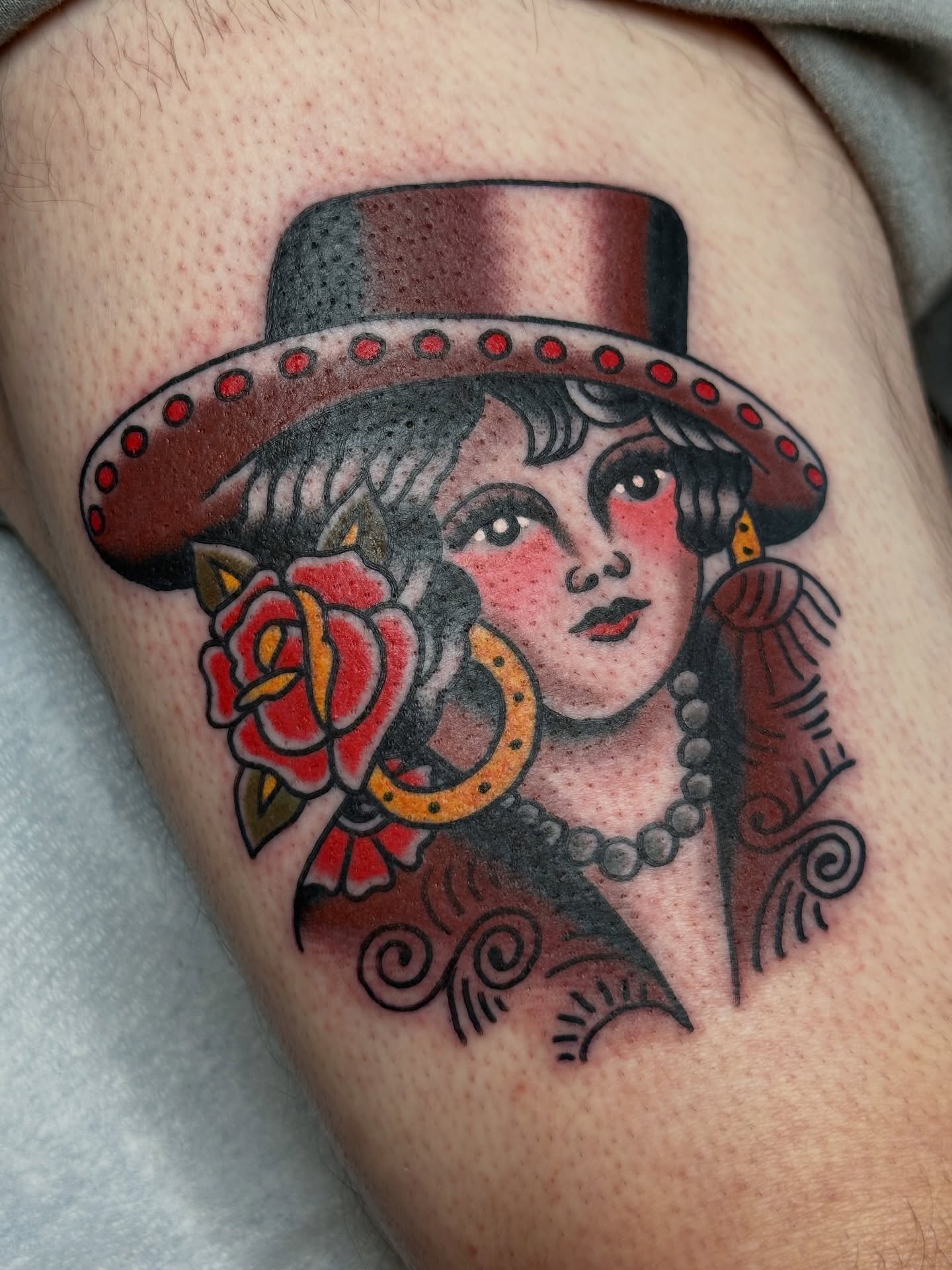 Woman with hat and rose American traditional tattoo on the thigh by Michael Williams